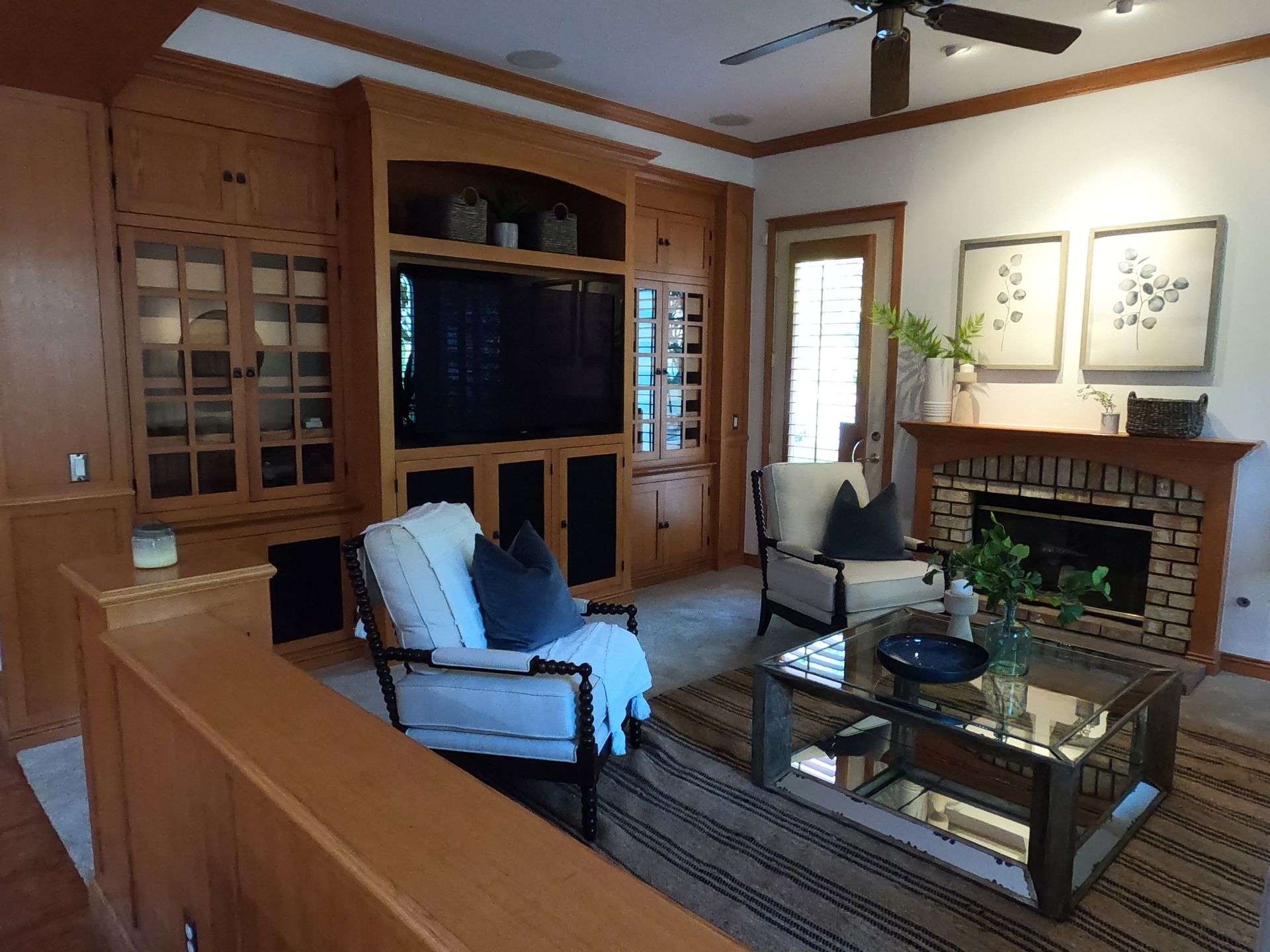 Living room with built-in cabinetry, fireplace, two chairs, and a glass coffee table.