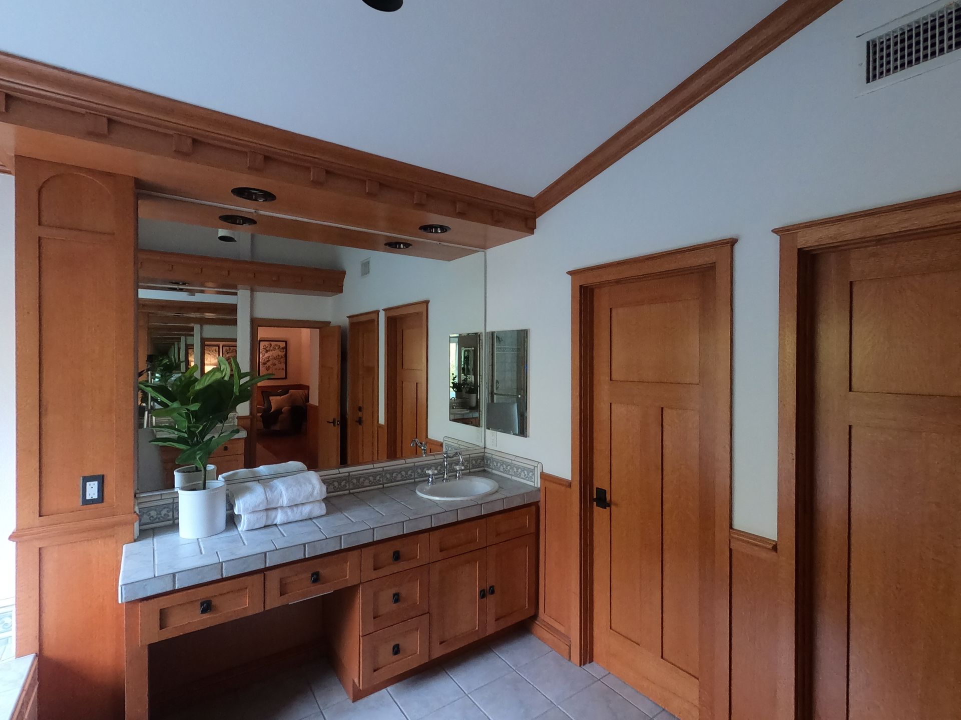 Bathroom with wood trim, cabinetry, and doors; a vanity with a mirror, sink, and towels.