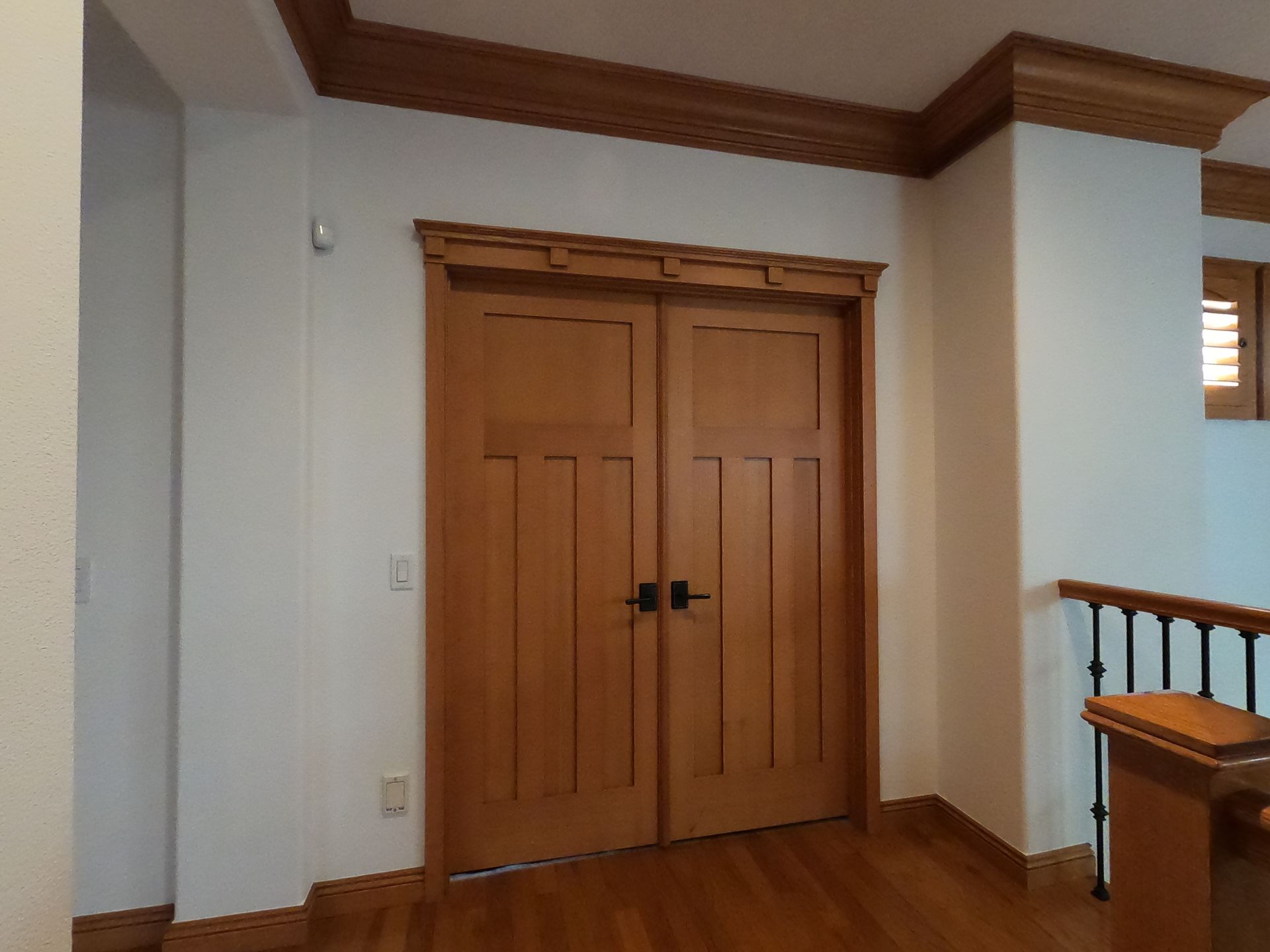 Wooden double doors in a room with light-colored walls and wood trim.