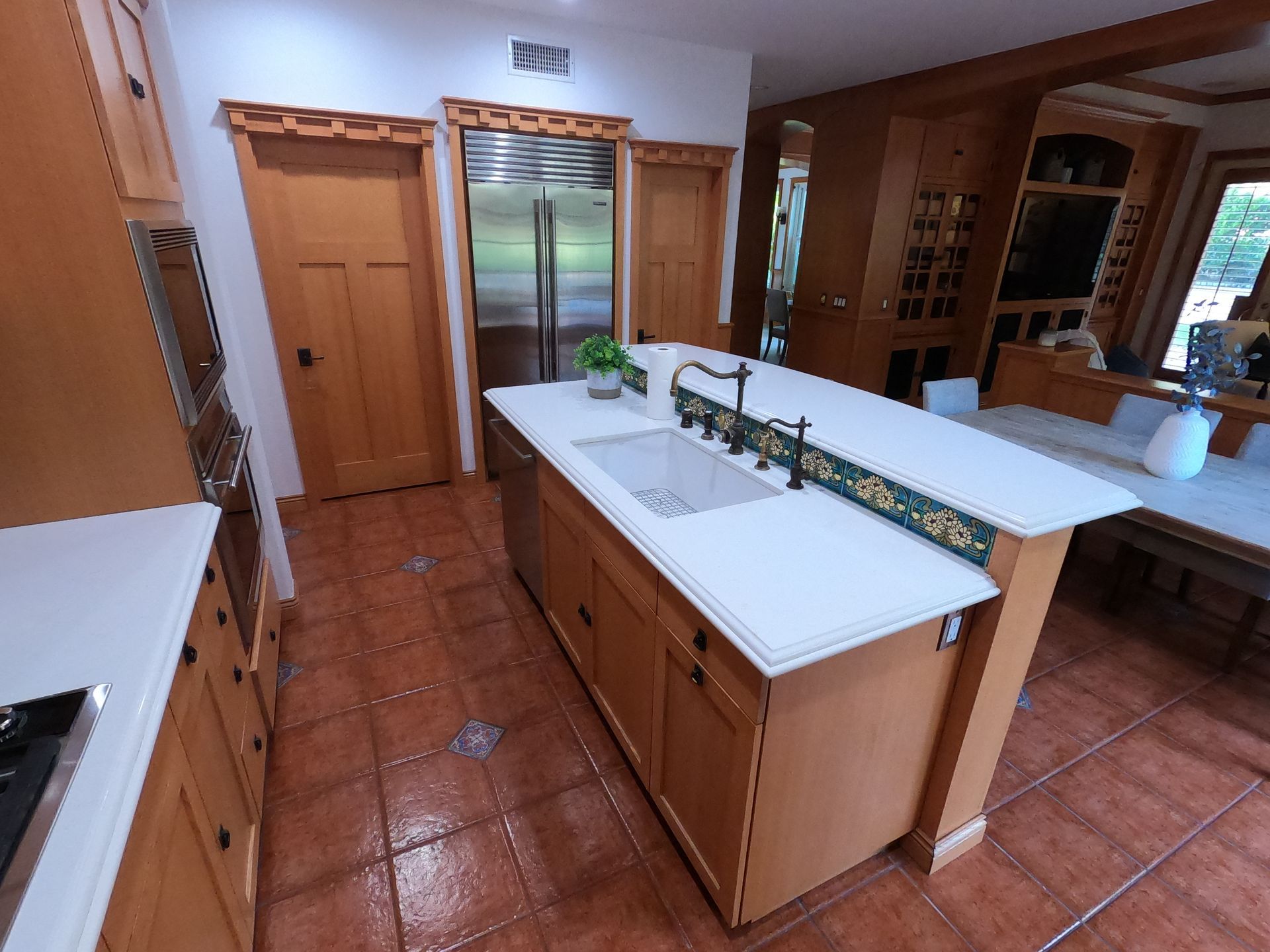 Kitchen with wood cabinets, stainless steel refrigerator, and large island with sink.