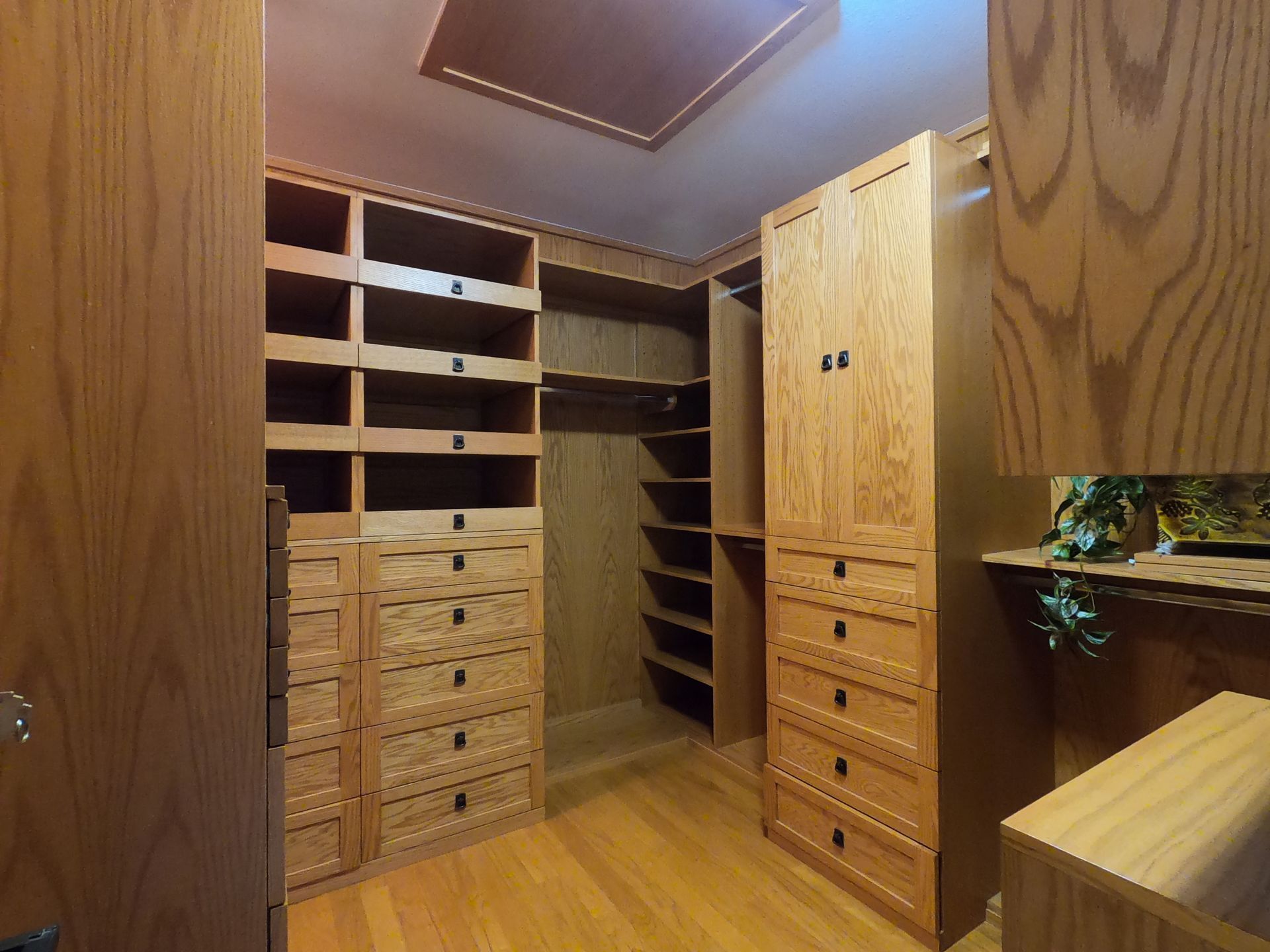 Walk-in closet with wooden shelves, drawers, and cabinetry, built-in and well-lit.