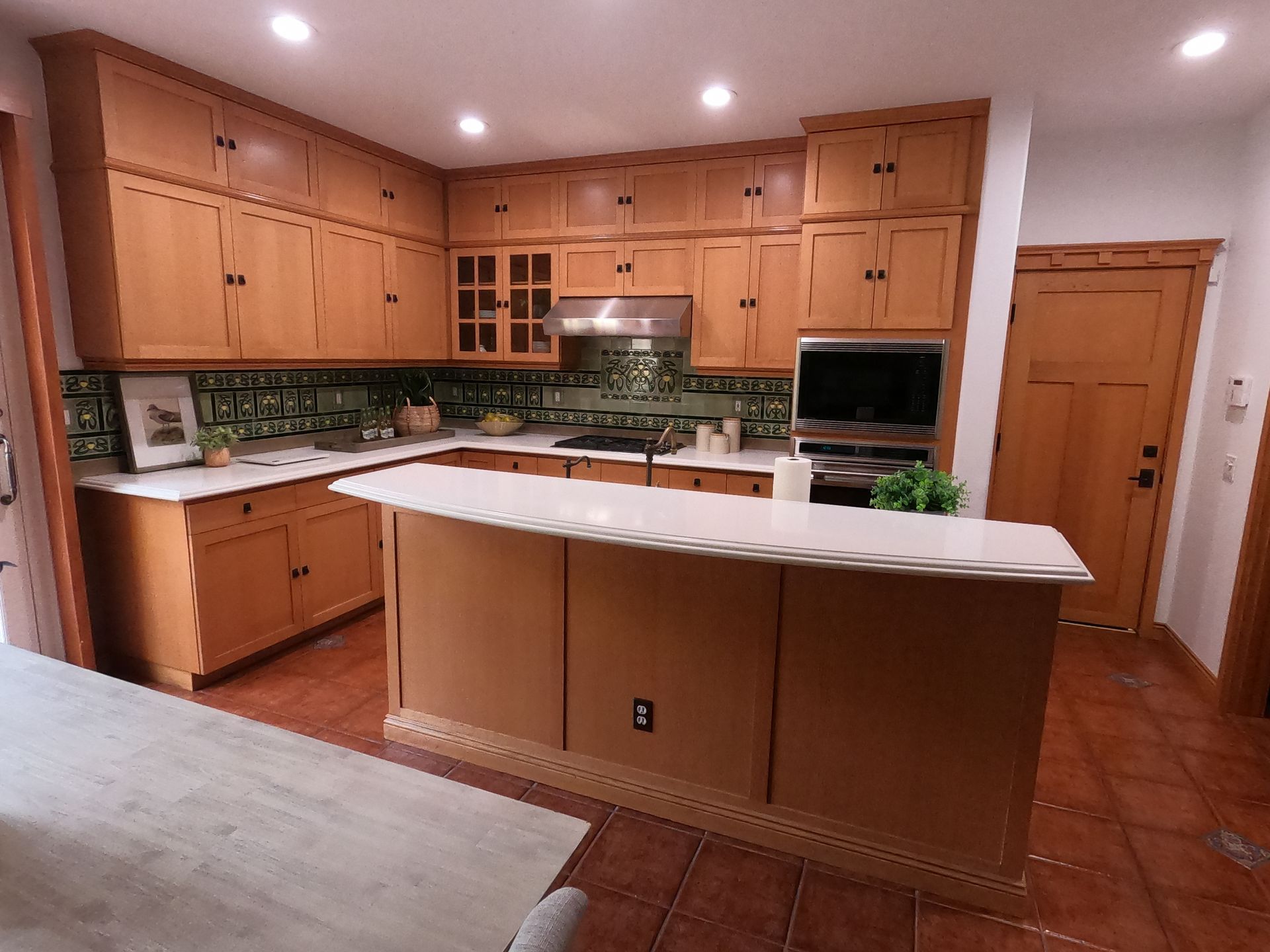 Kitchen with wooden cabinets, white countertops, and an island.