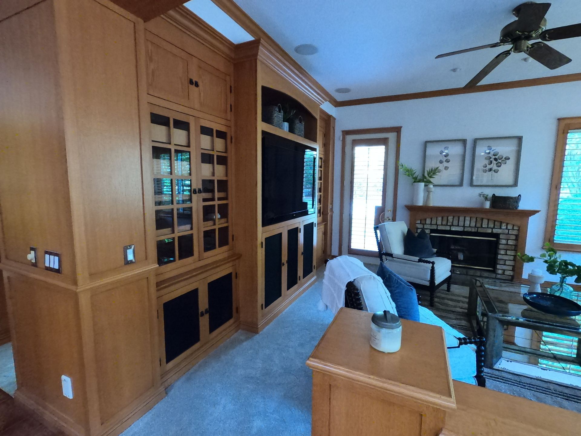 Wooden built-in entertainment center, fireplace, and seating area in a living room.