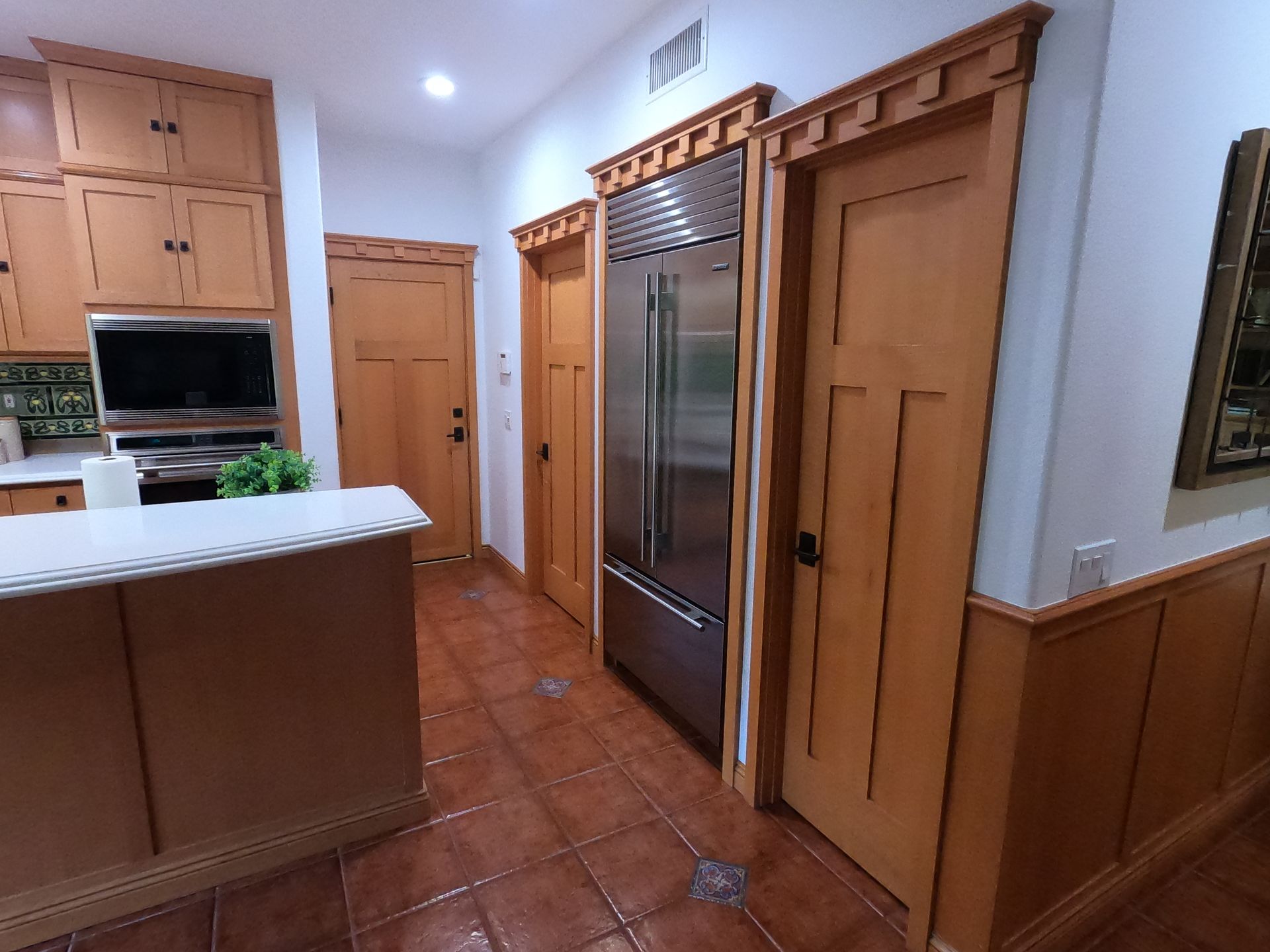Kitchen with wood cabinets, doors, and stainless steel refrigerator.