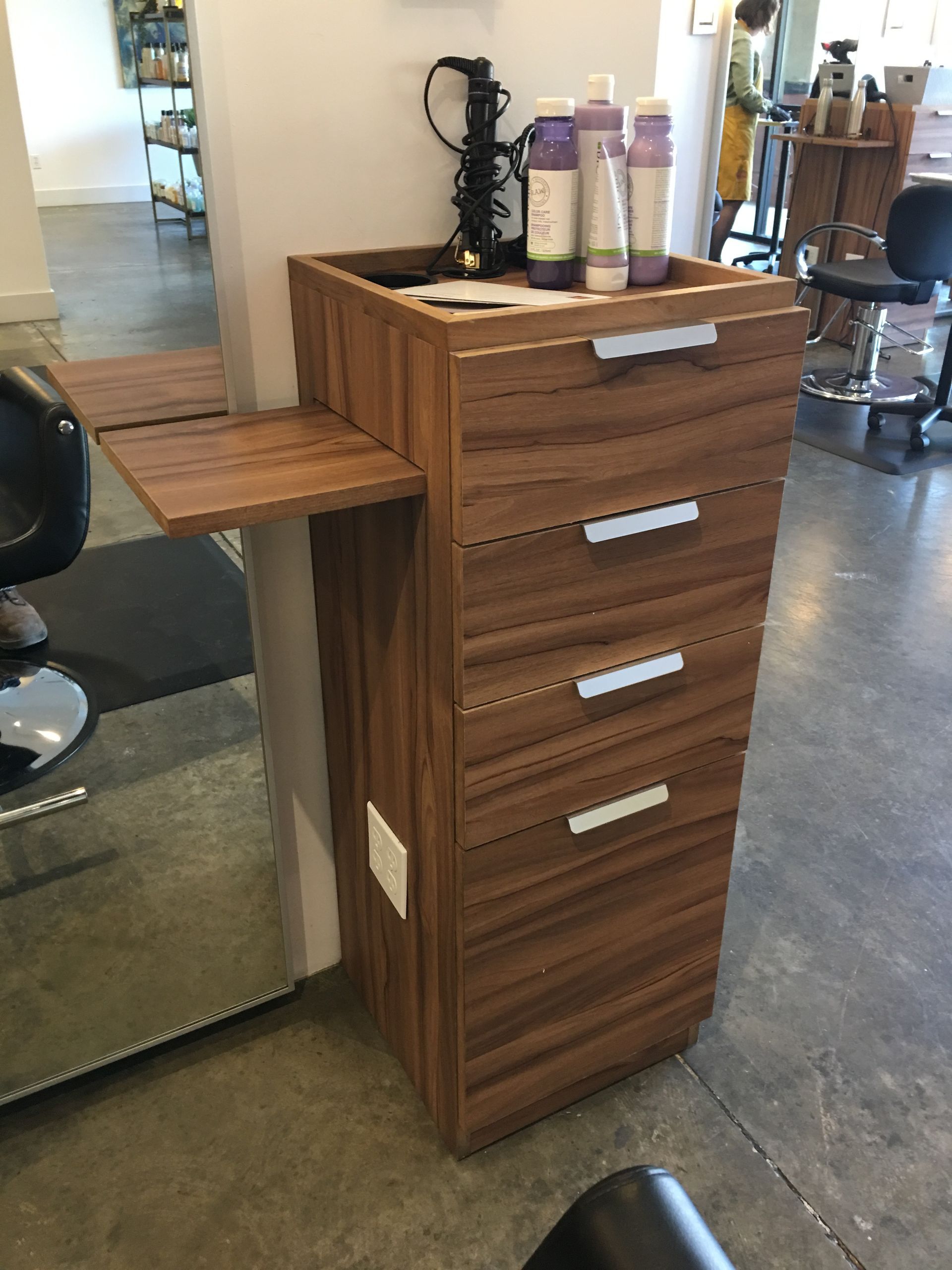 Wooden cabinetry in a kitchen area with a countertop, appliances, and a small bar with seating.
