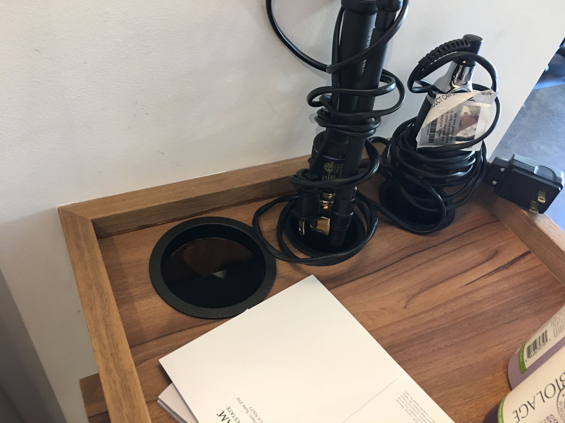 Wooden tray with black hair curling iron, power cords, and documents.