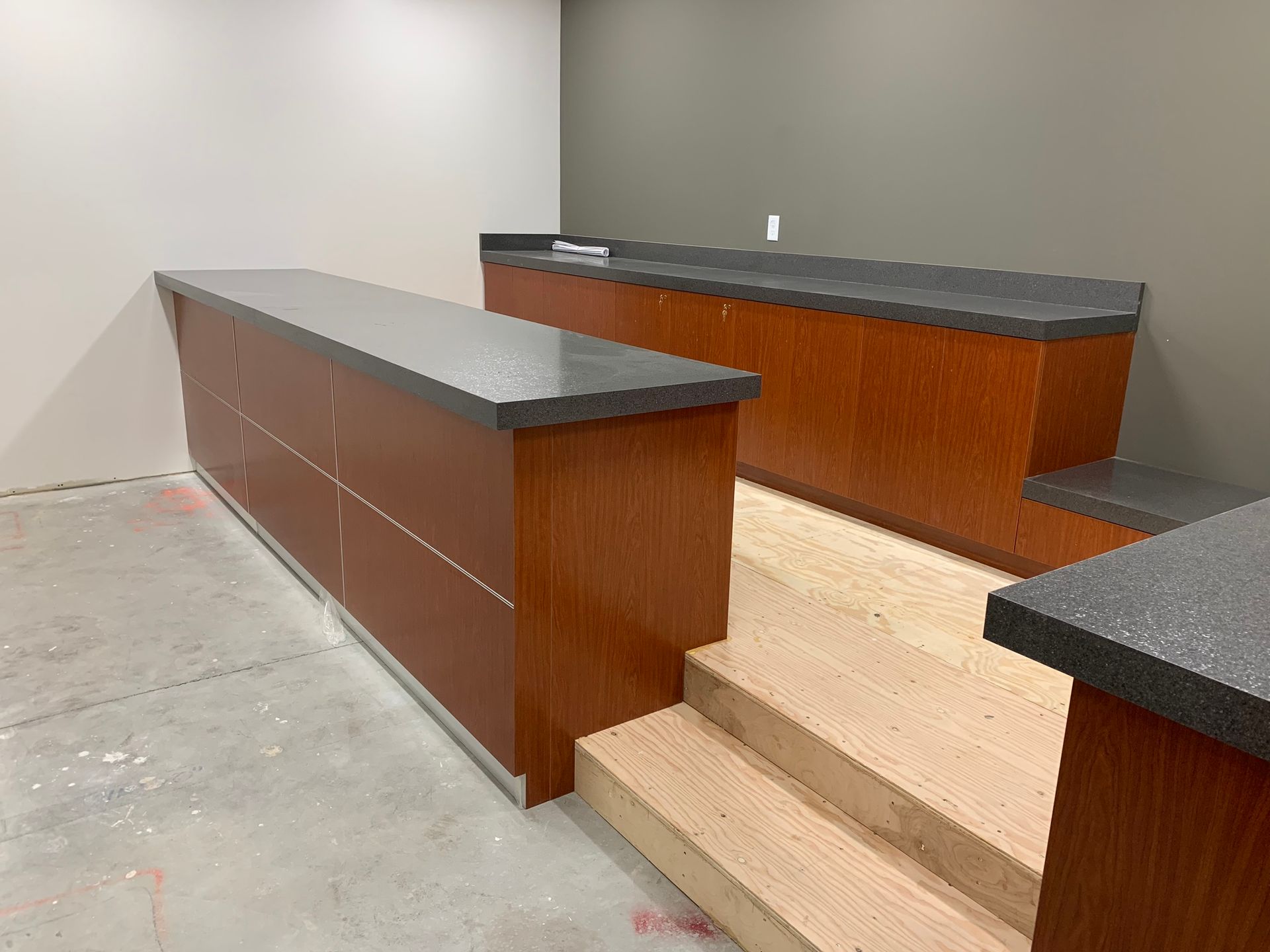 Wooden bar inside a dimly lit space with bottles, taps, and arcade game visible.