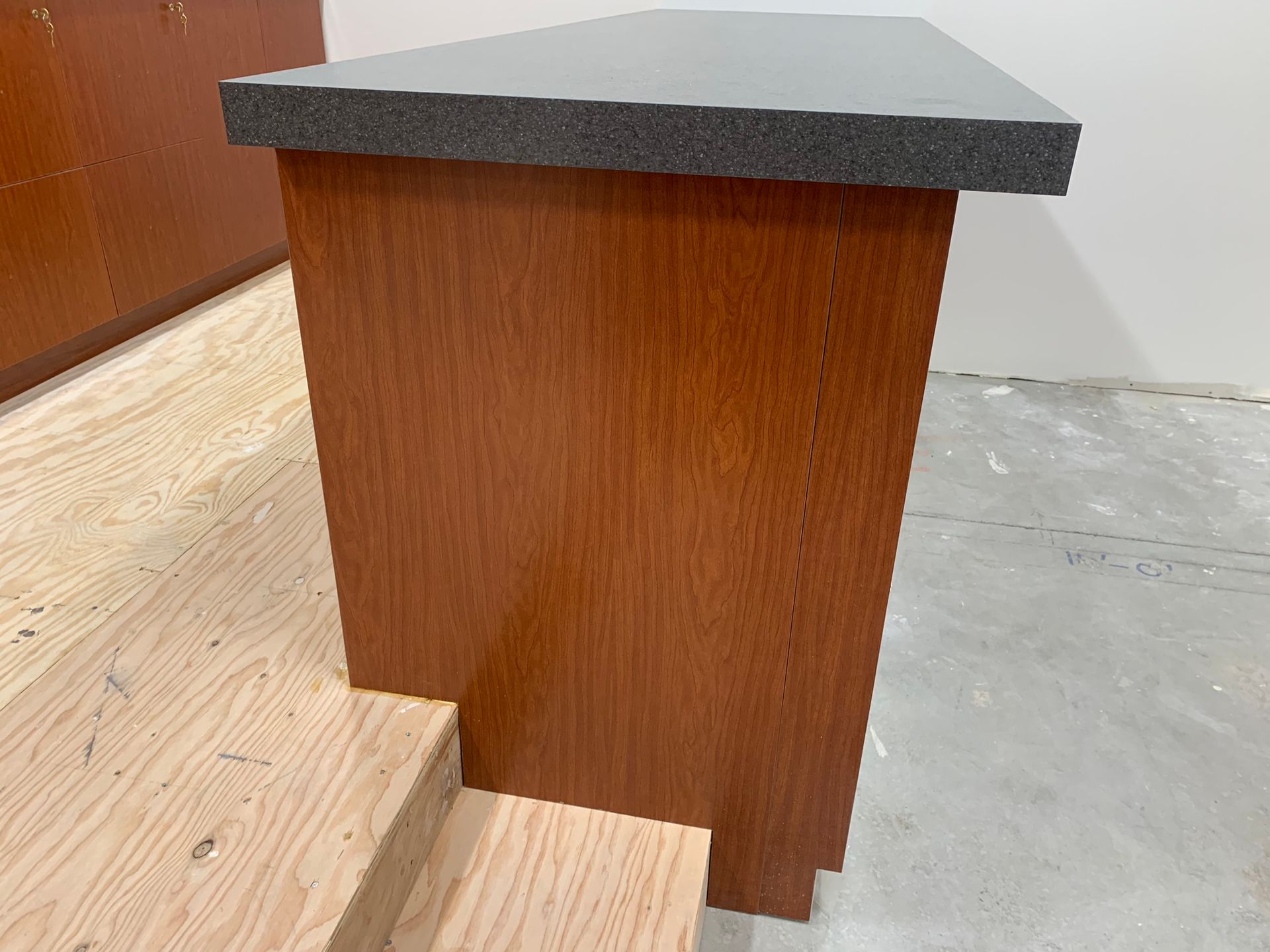 Wooden cabinet with a dark gray countertop on a light wood step.