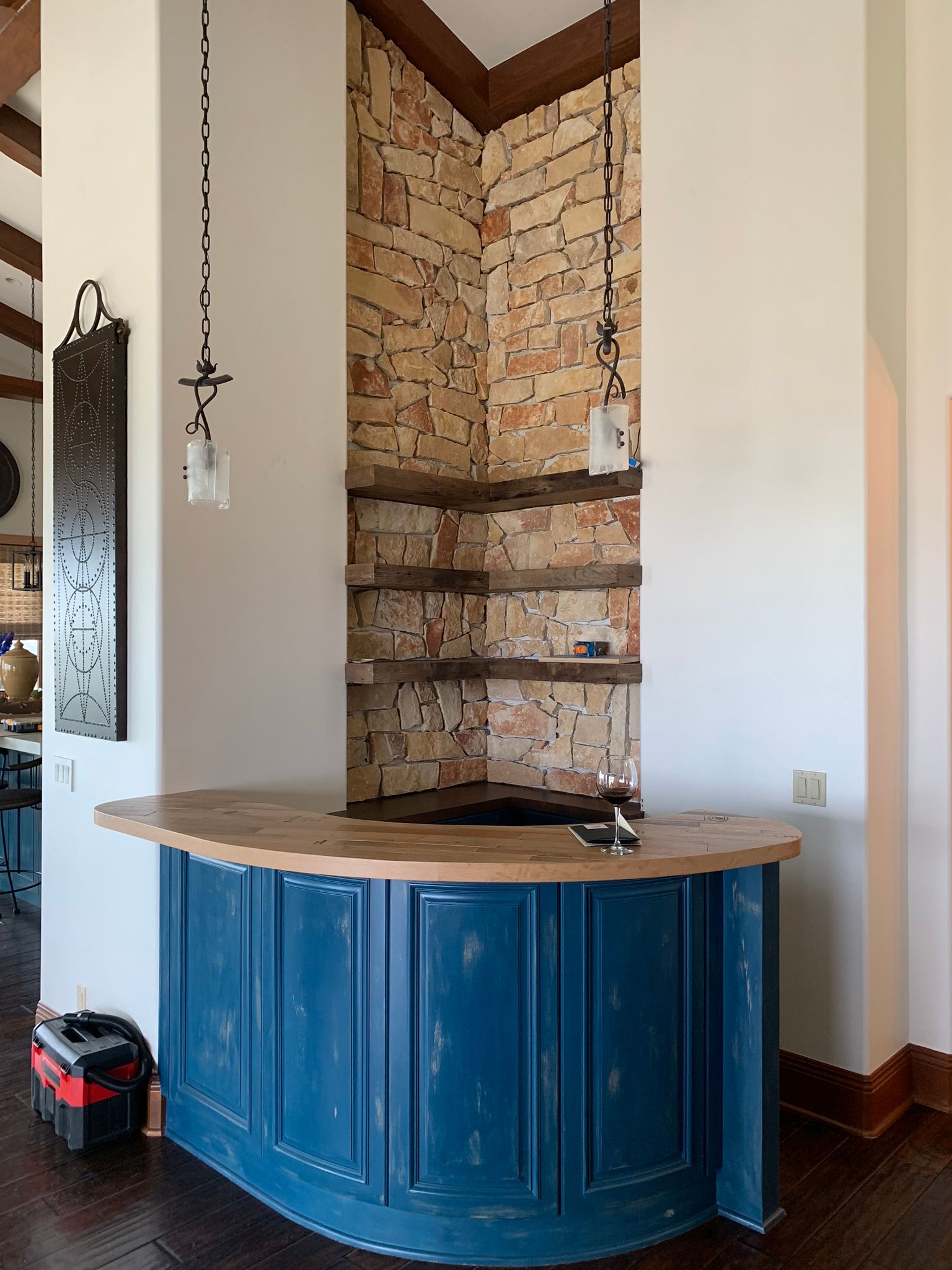 Blue and wood bar with stone accent wall and shelves.
