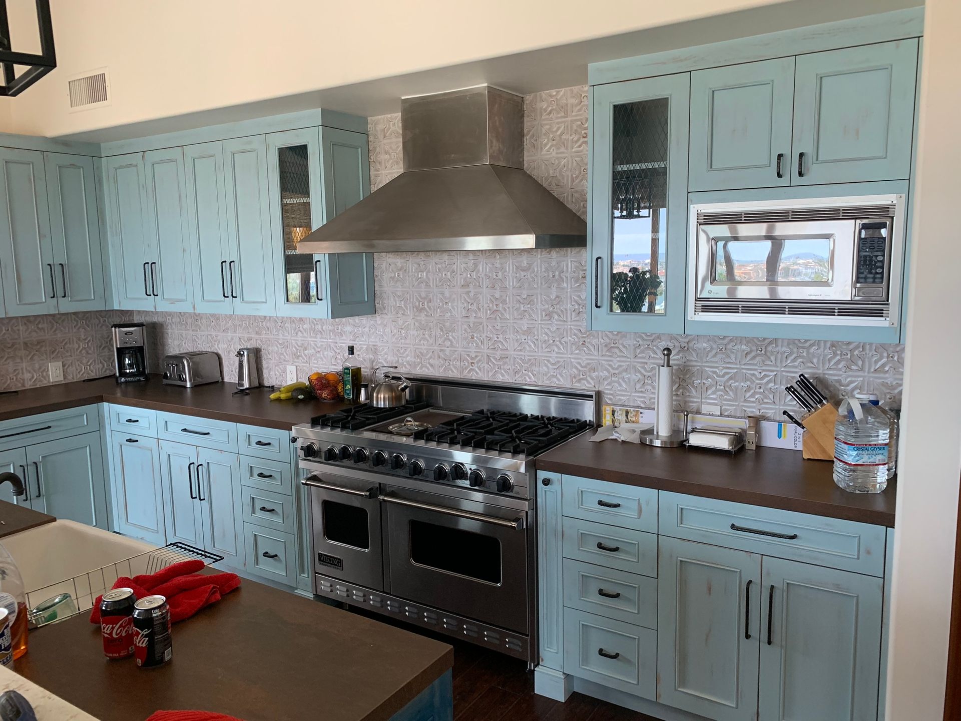 Light blue kitchen with dark countertops, stainless steel appliances, and a mosaic backsplash.