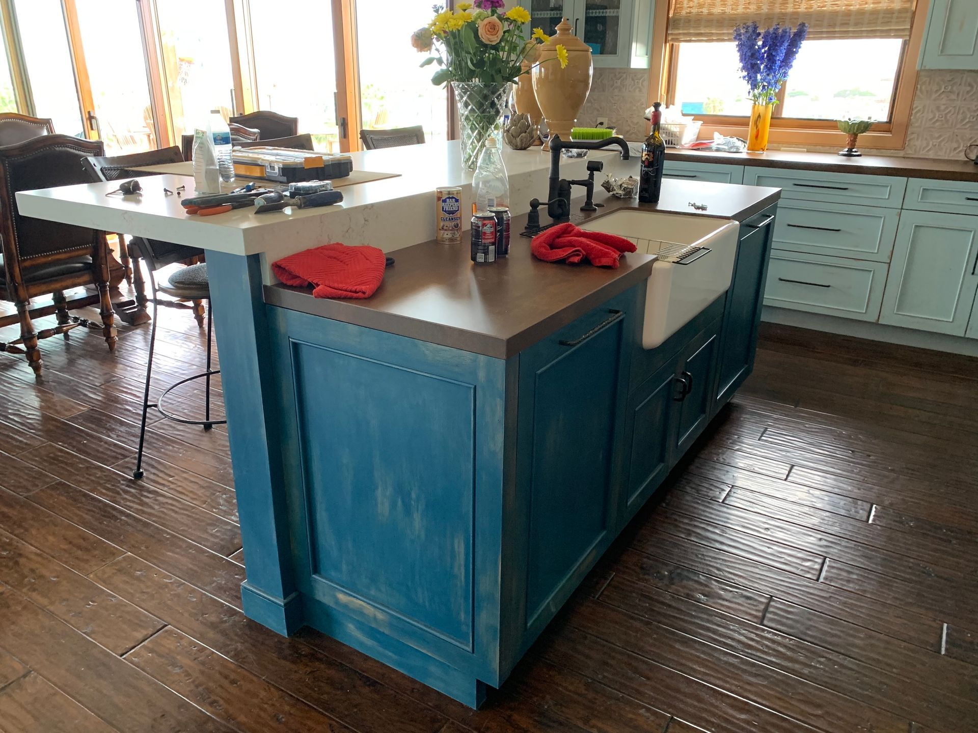 Blue kitchen island with concrete countertop, farmhouse sink, and wooden floor.