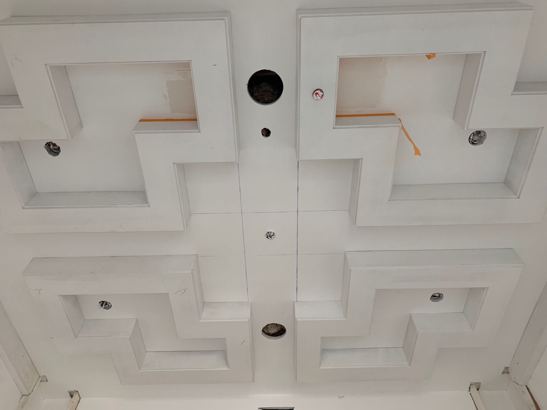 White ceiling with recessed geometric designs and circular light fixtures.