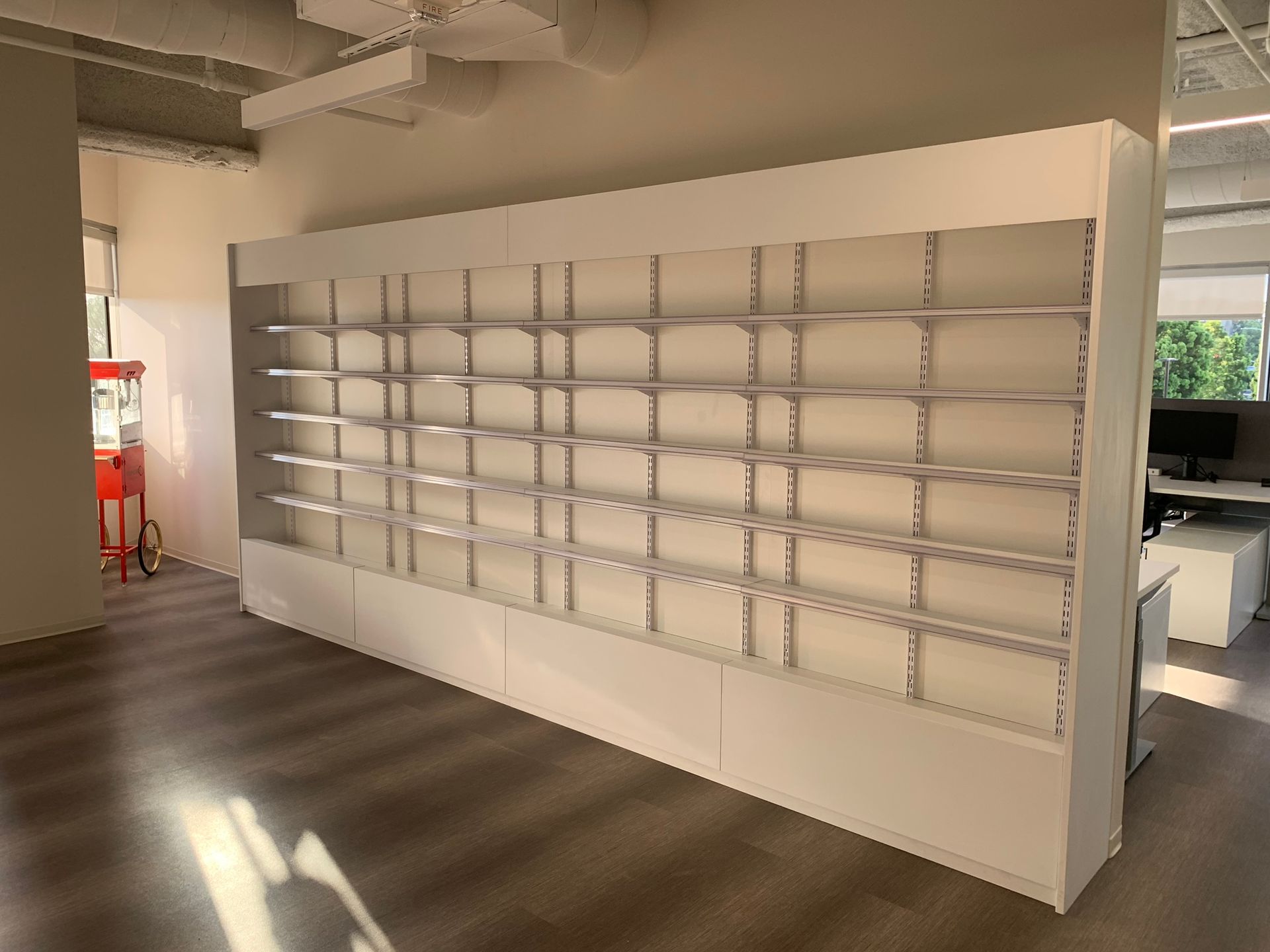 Empty white shelving unit against a white wall in an office setting.
