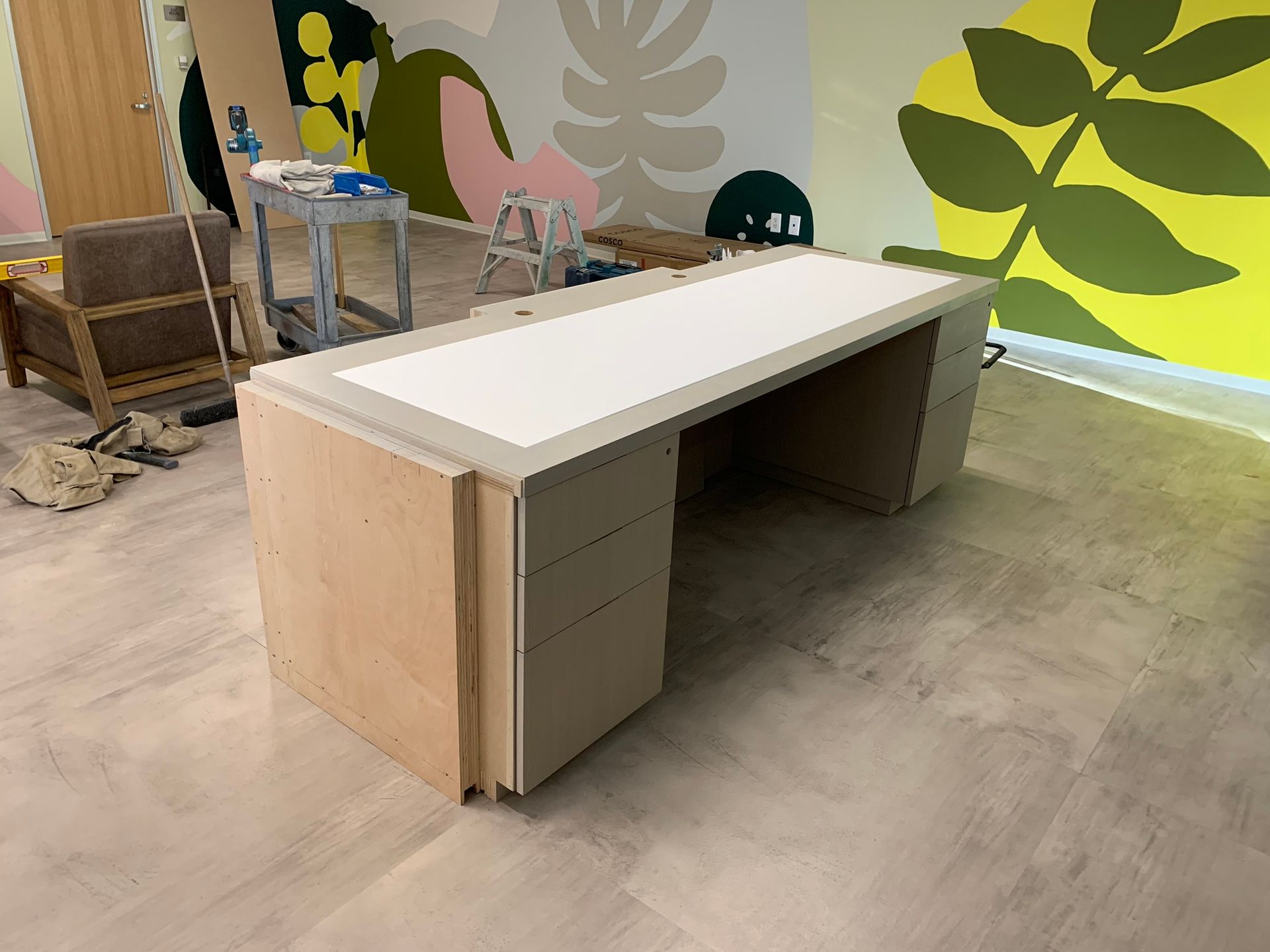 Wooden desk with a white top and gray trim in a brightly painted room.