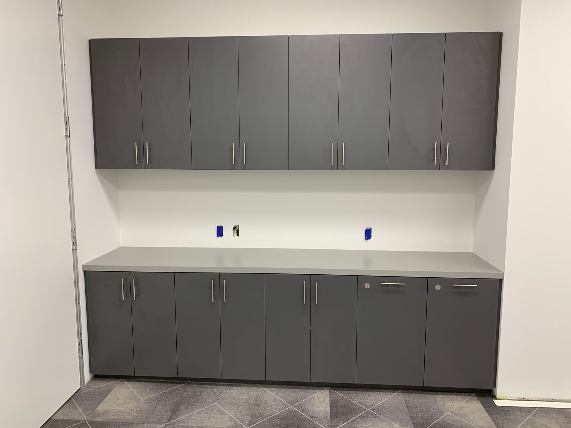 Gray cabinets on a gray countertop against a white wall.