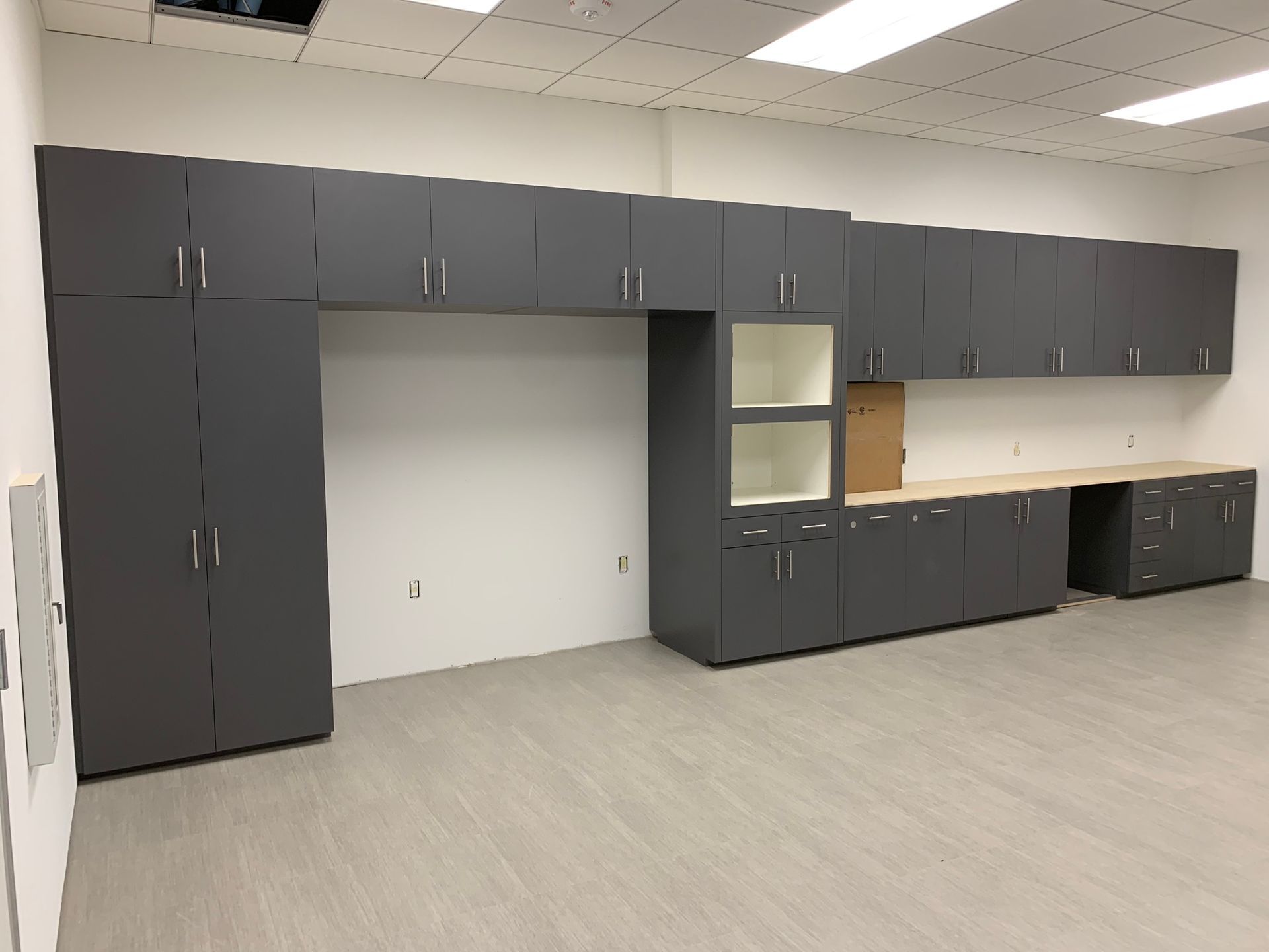 Gray cabinets installed in a room with light-colored flooring and ceiling.