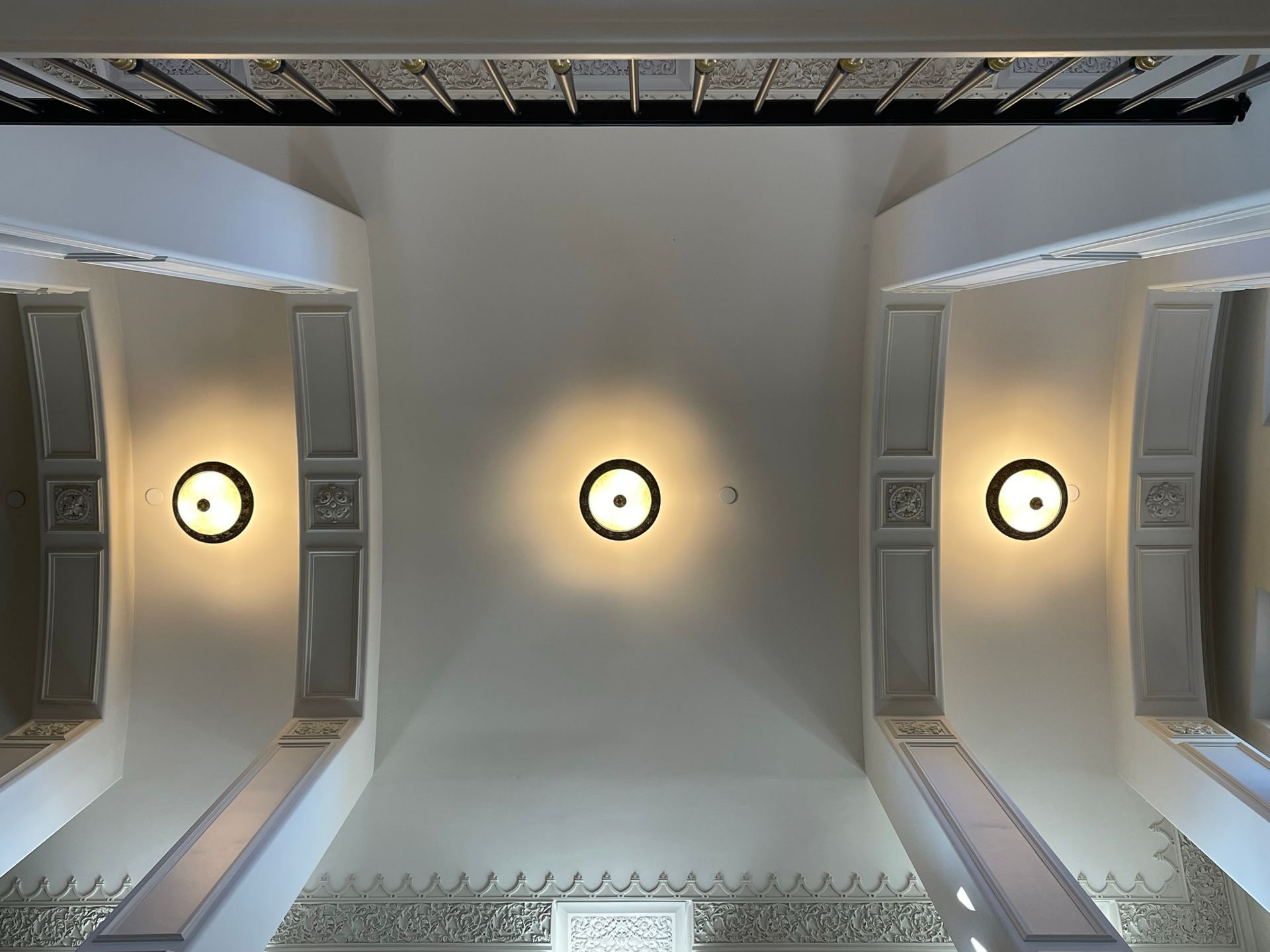 View of a white ceiling with three circular lights and decorative trim.