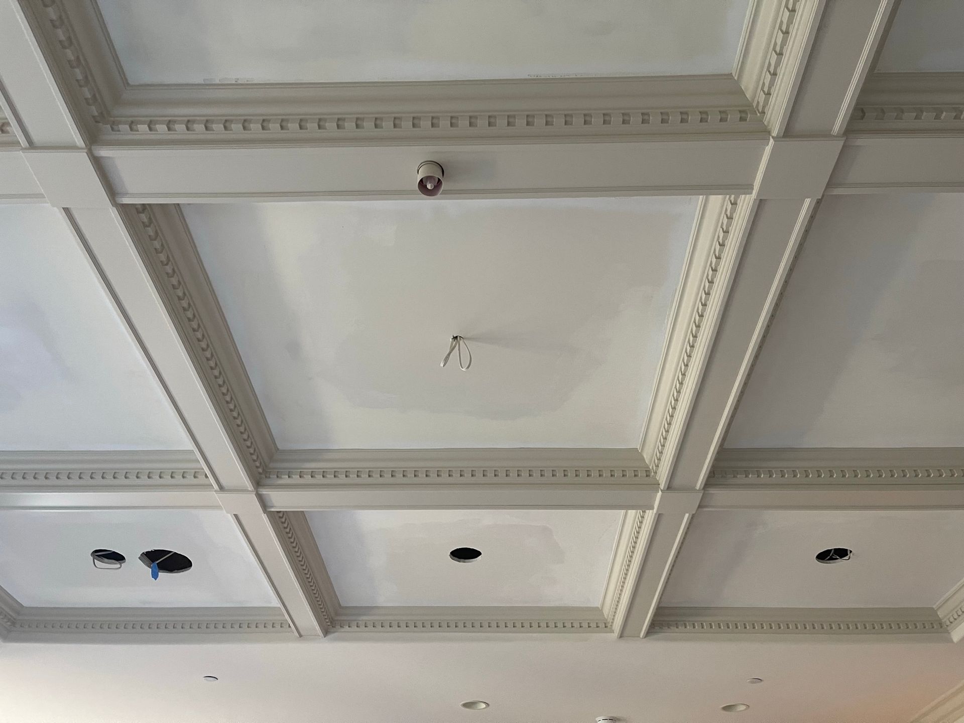 White coffered ceiling with crown molding and recessed light fixtures.