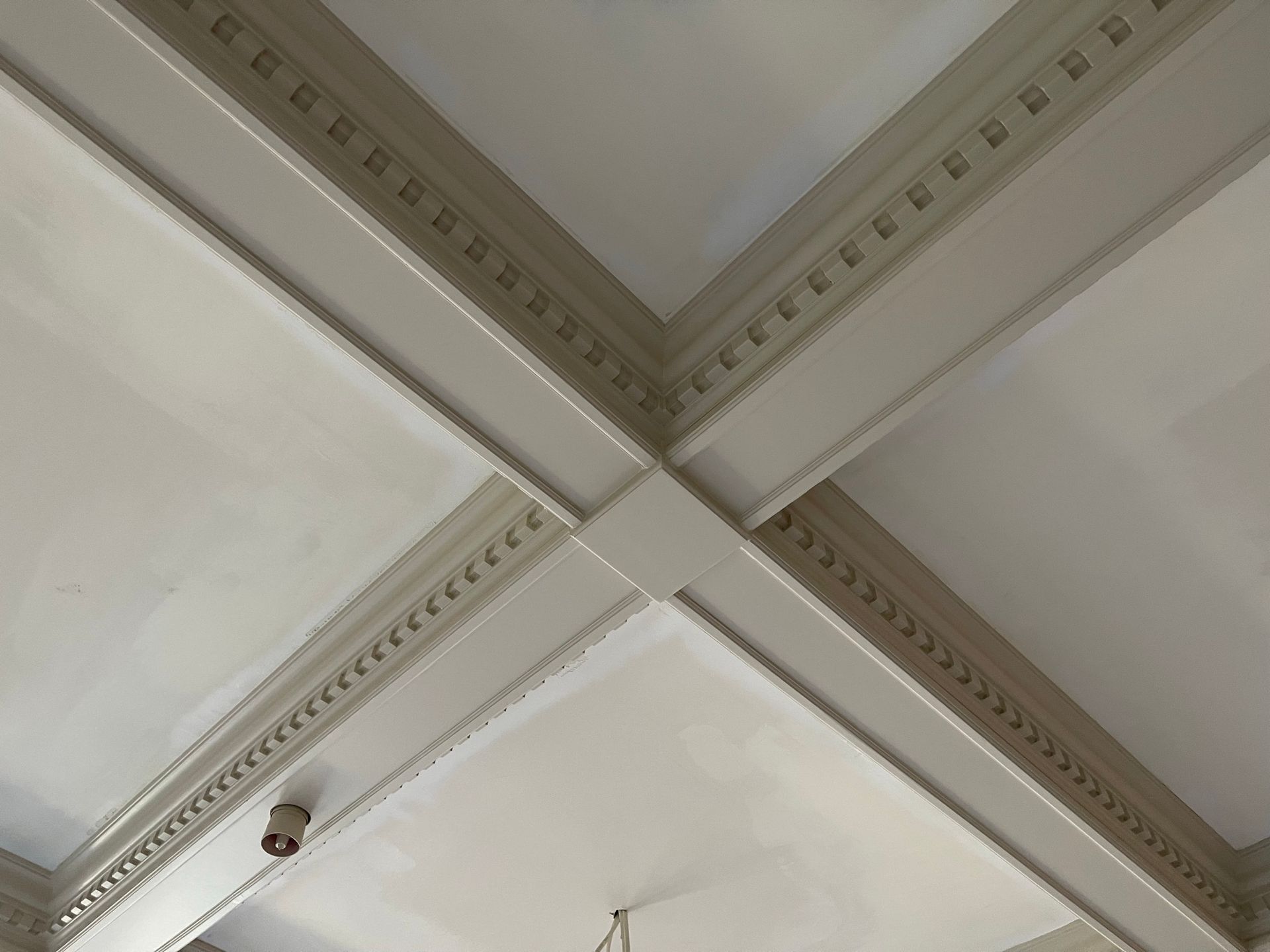 White ceiling with intersecting beams featuring decorative molding.