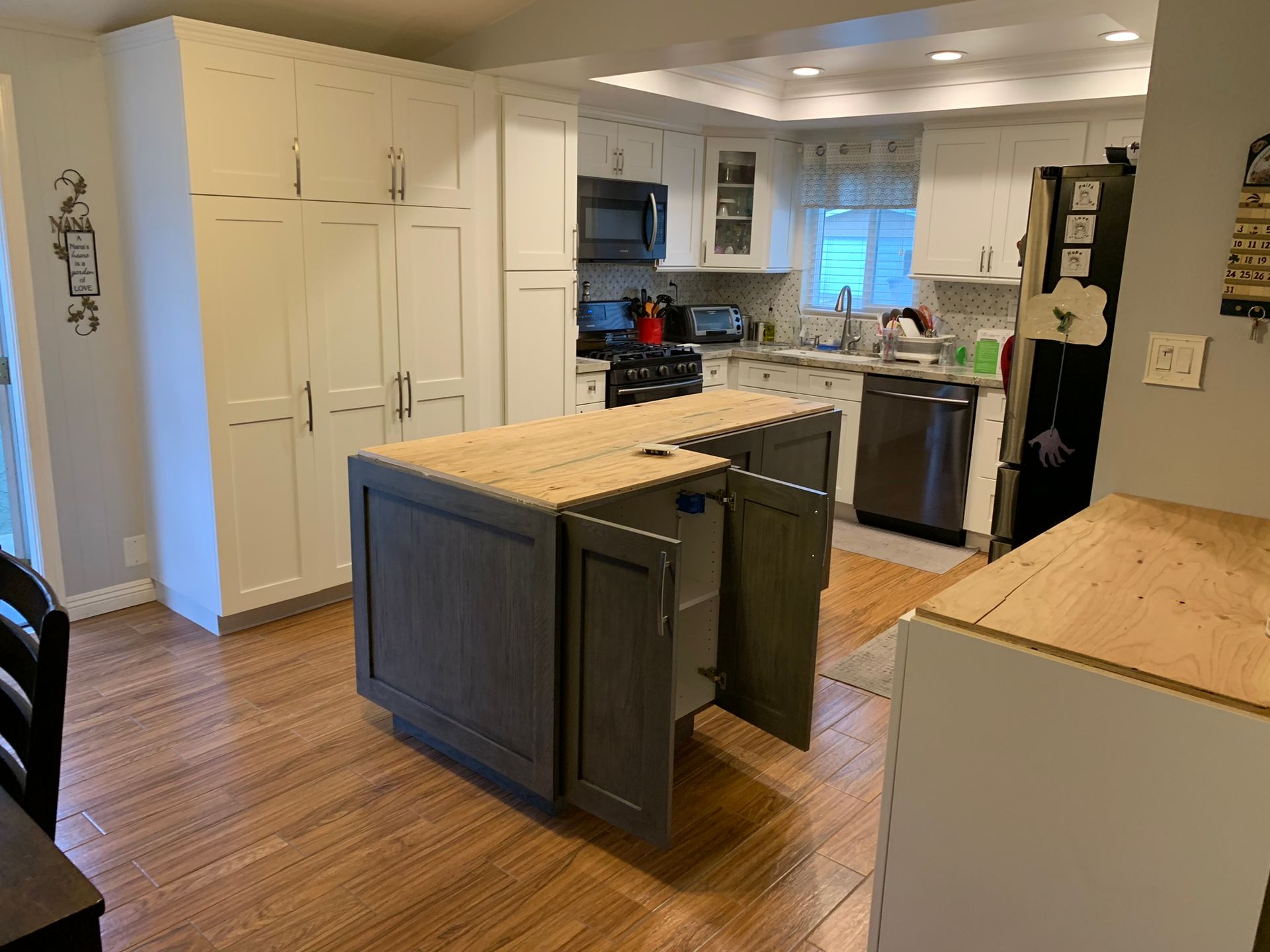 Kitchen with white cabinets, wooden island, stainless steel appliances, and wood flooring.