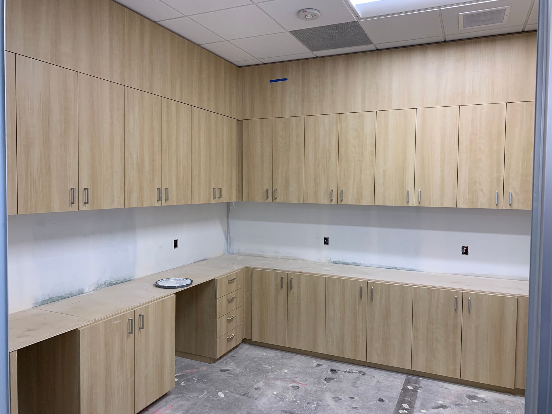 Light wood cabinets and countertops in a room under construction.
