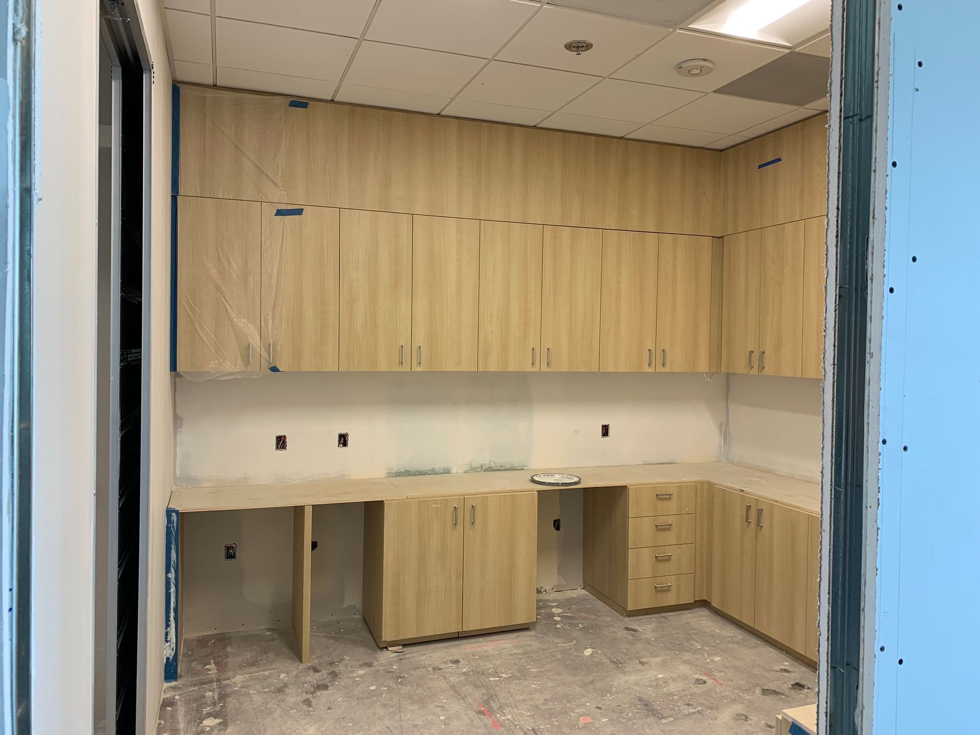 Room with light wood cabinets, countertop, and unfinished walls, viewed from a doorway.