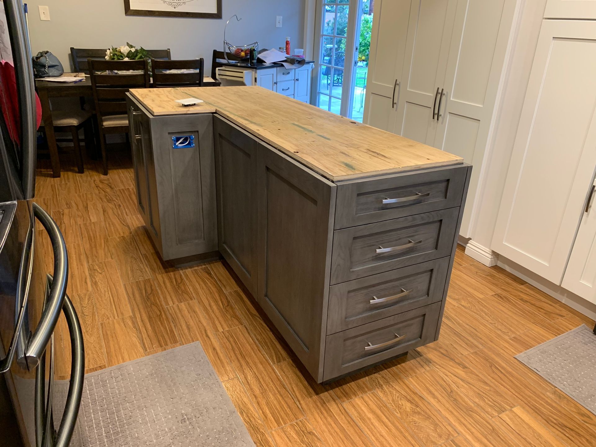 Gray kitchen island with light wood countertop and drawers on a wood floor.