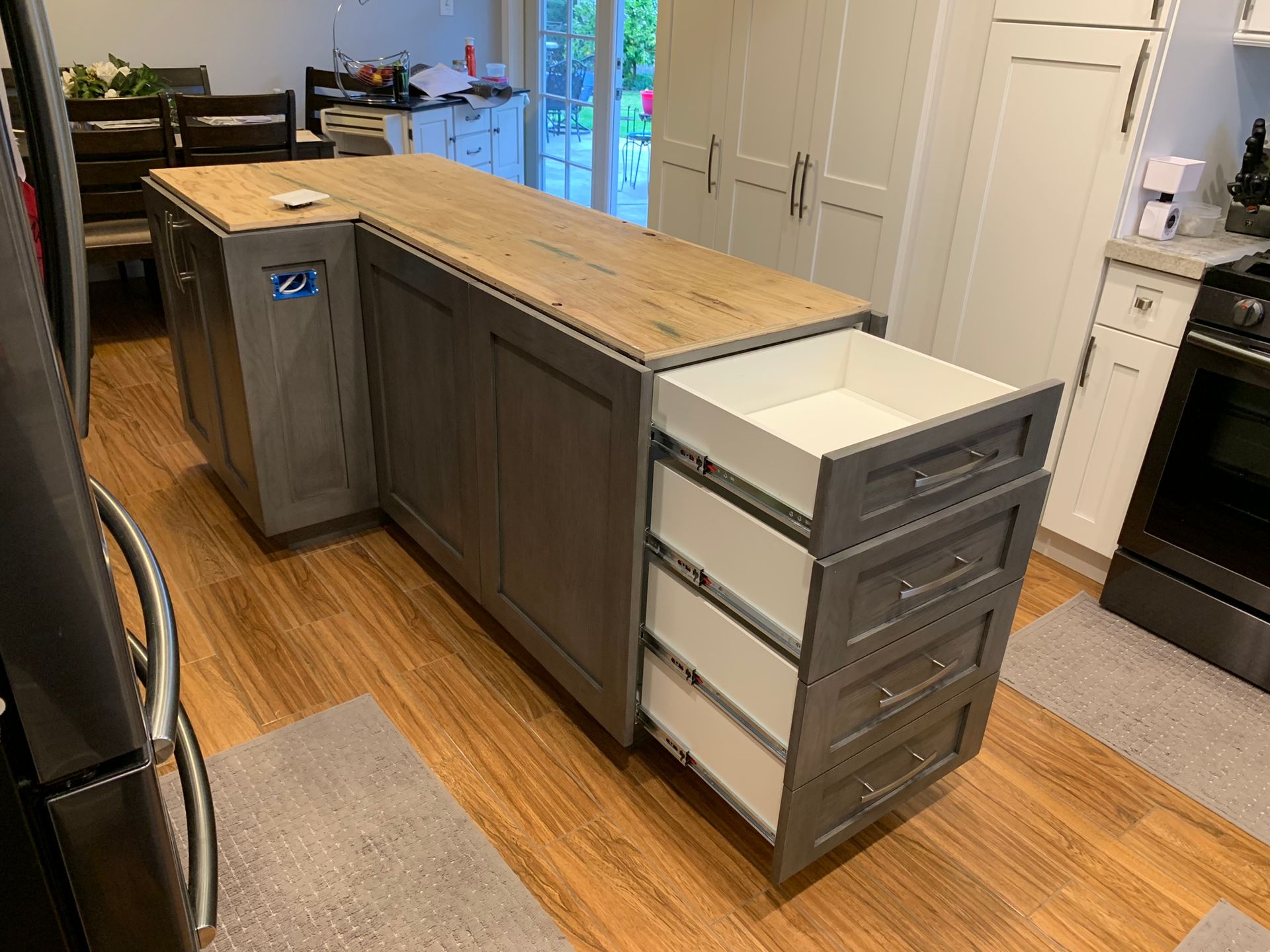 Kitchen island with gray cabinets, wood countertop, and open drawers; wood floor.