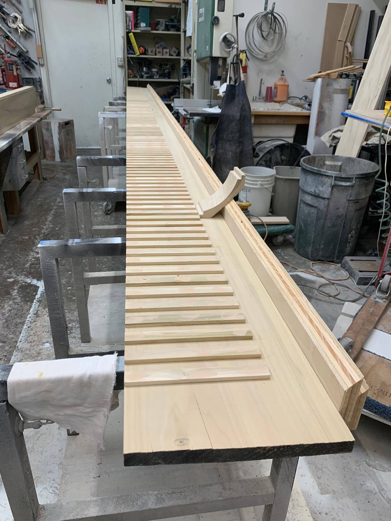 Long wooden planks with cut grooves, in a workshop setting.