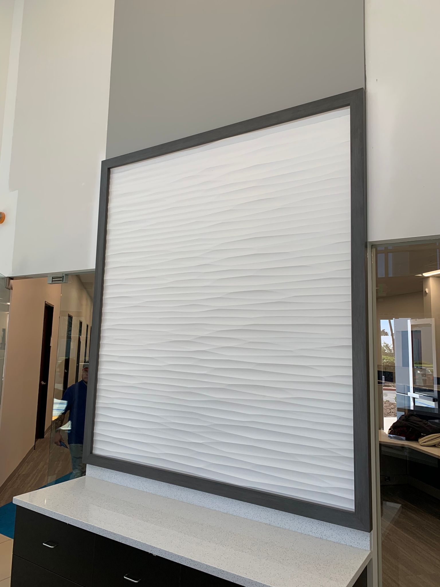 White textured wall panel with dark gray frame on countertop.