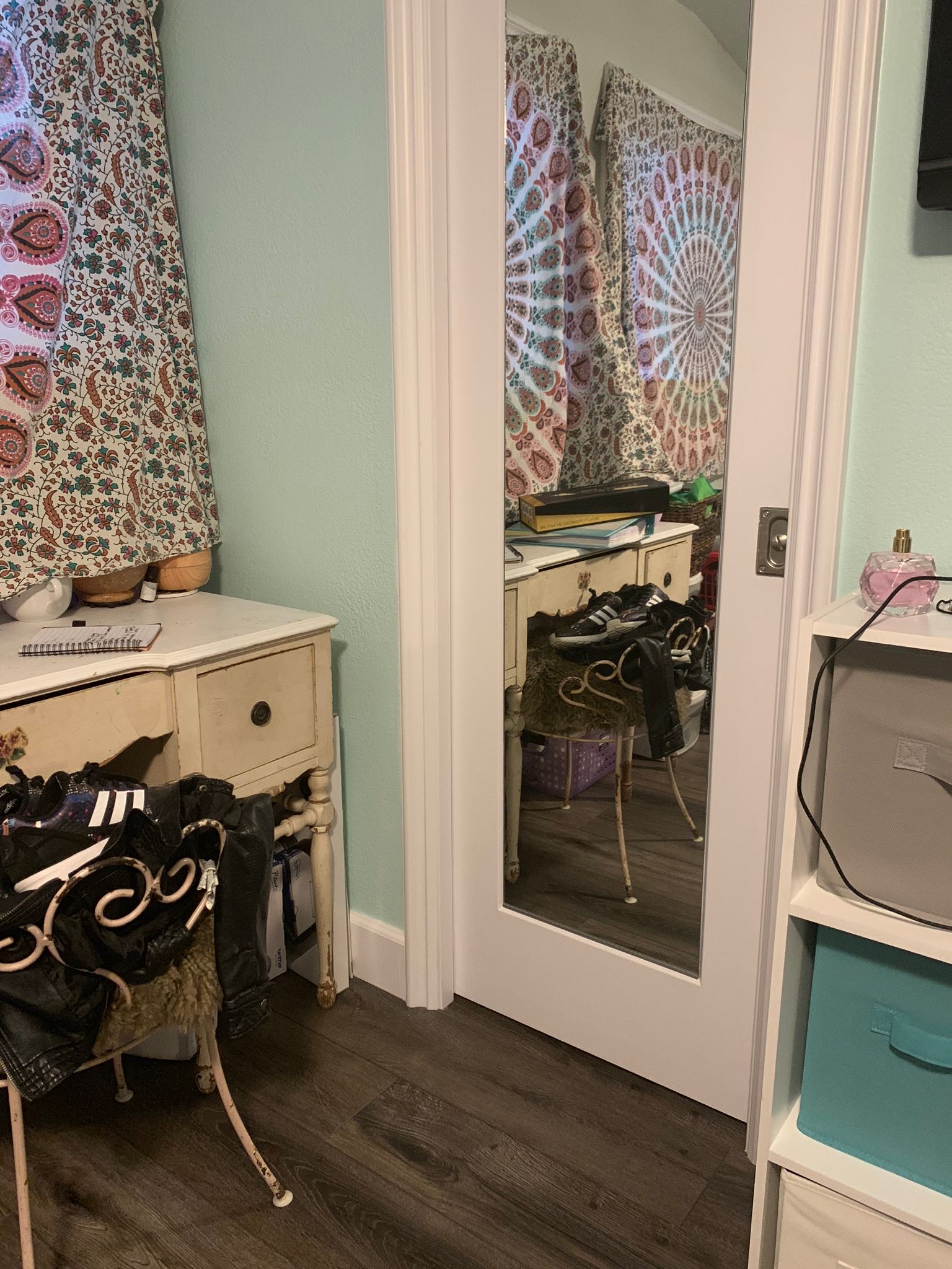 Room interior with a doorway reflecting another room, a desk, and a curtain.