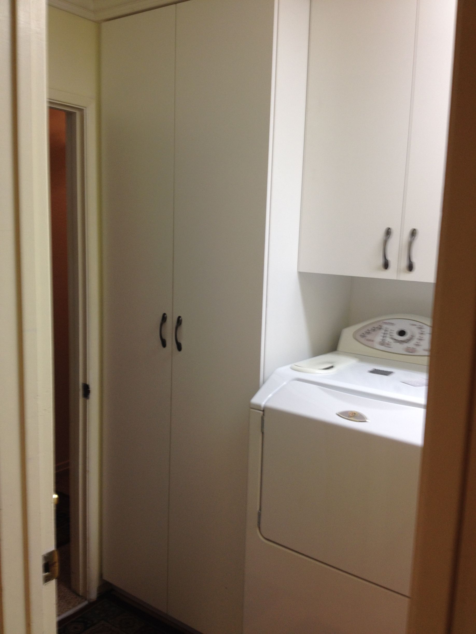 Laundry room with white cabinets and a washing machine. A doorway is to the left.