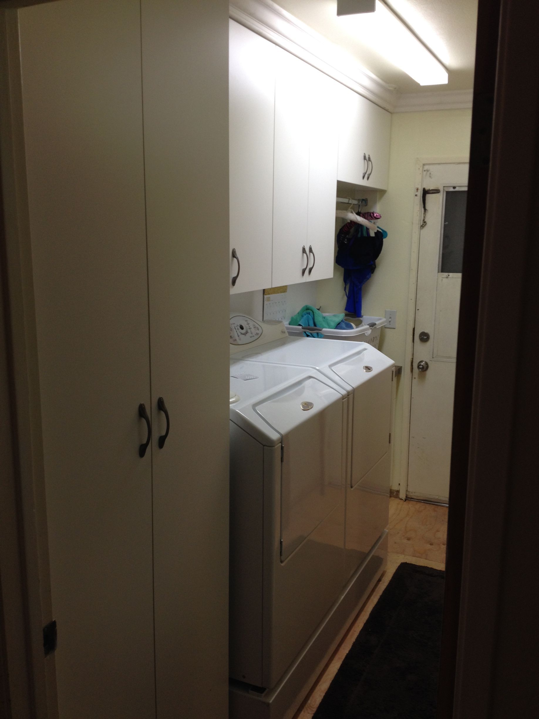 Laundry room with white cabinets, washer/dryer, and a doorway.