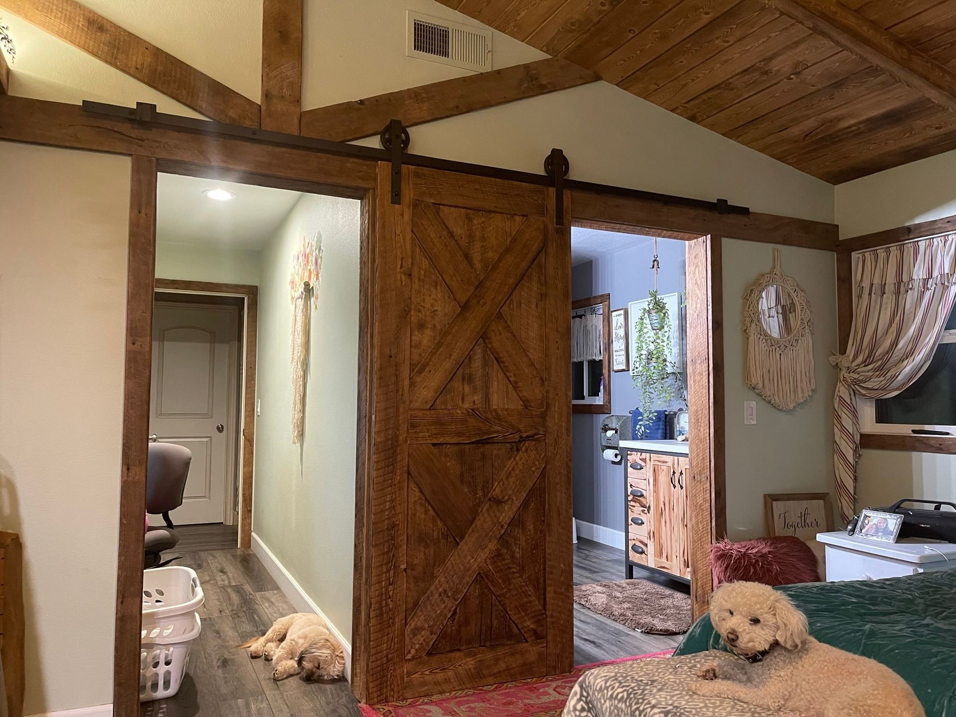Wooden barn door between rooms, two dogs resting, rustic interior.