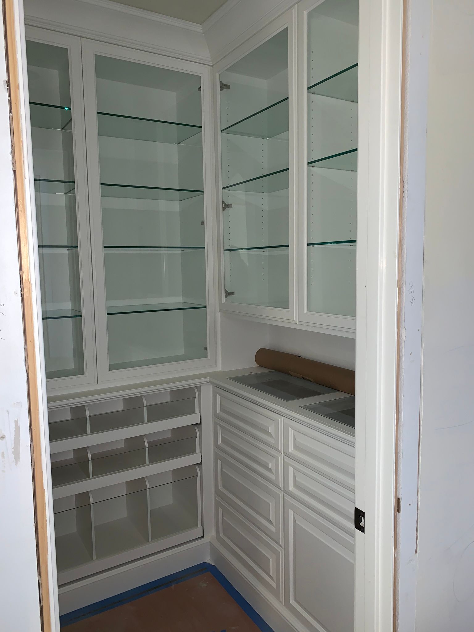 White pantry cabinets with glass doors, drawers, and open shelving.