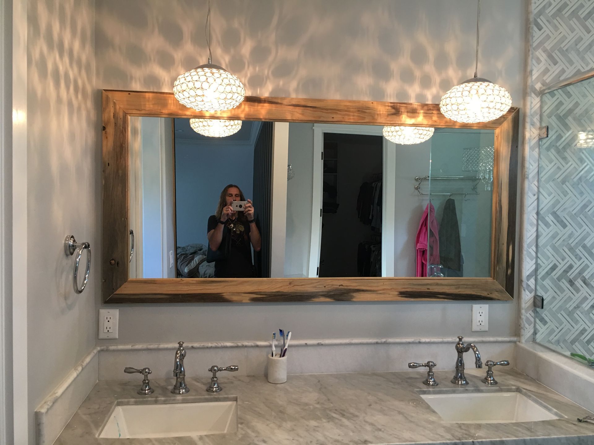 Bathroom with large mirror, two sinks, and two globe pendant lights, marble countertop.