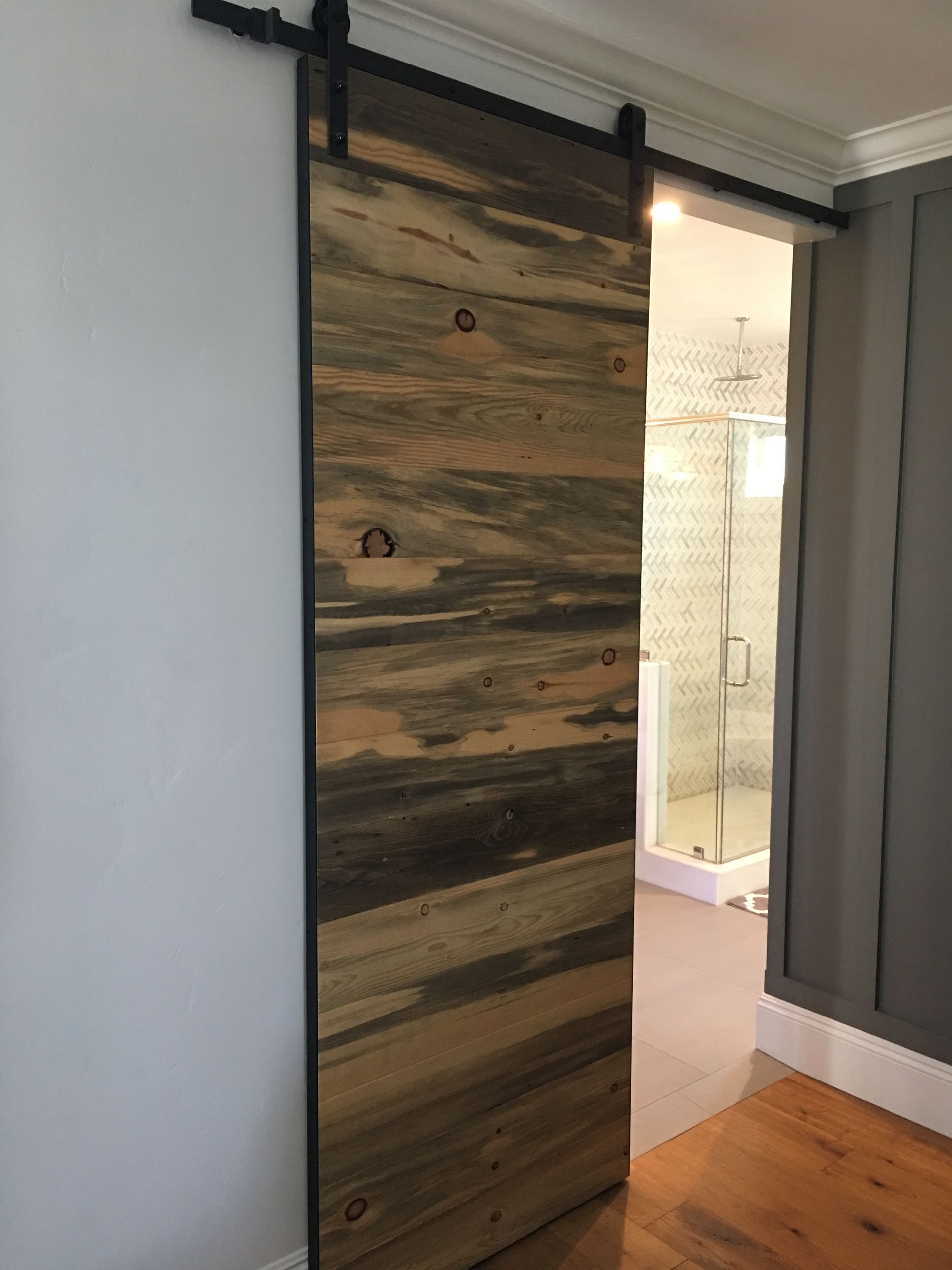 Barn door made of wood, open doorway to bathroom.