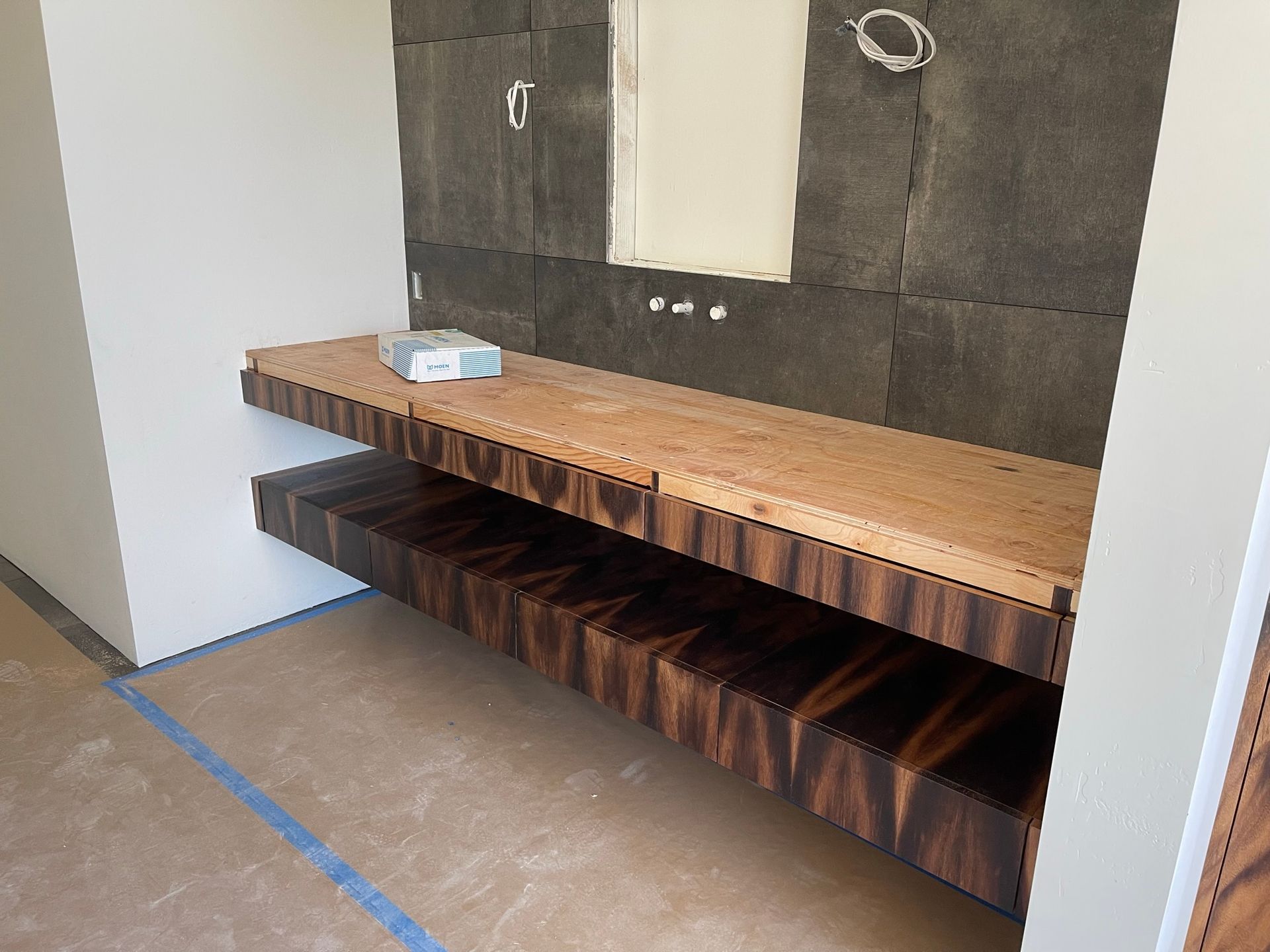 Floating wooden shelves in a bathroom under construction; one shelf light, the other dark wood.