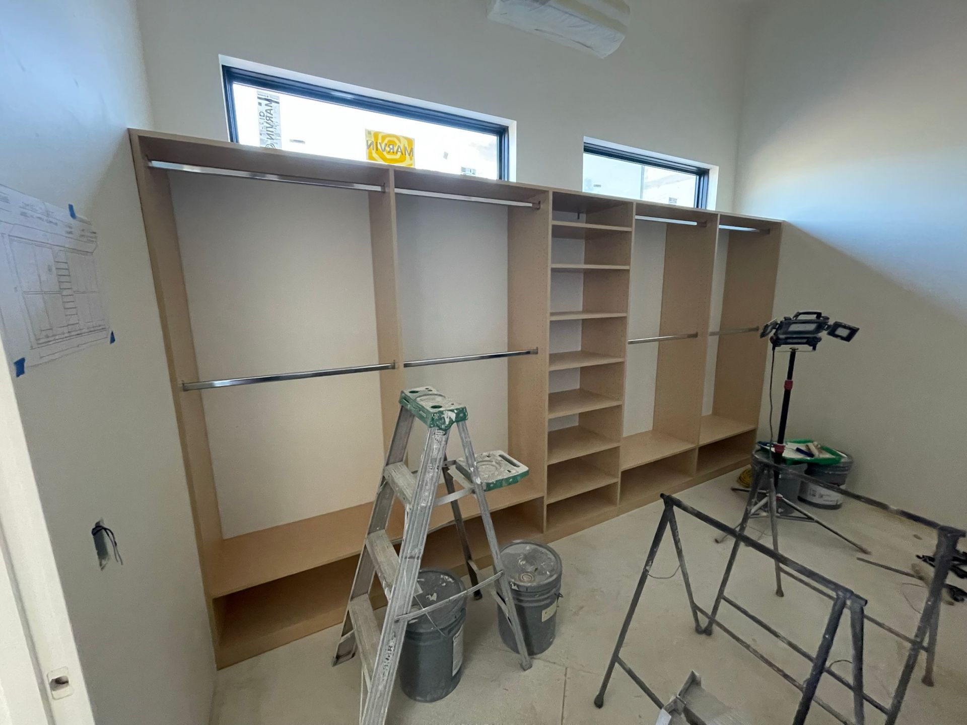 Walk-in closet under construction with shelves, rods, and ladder.