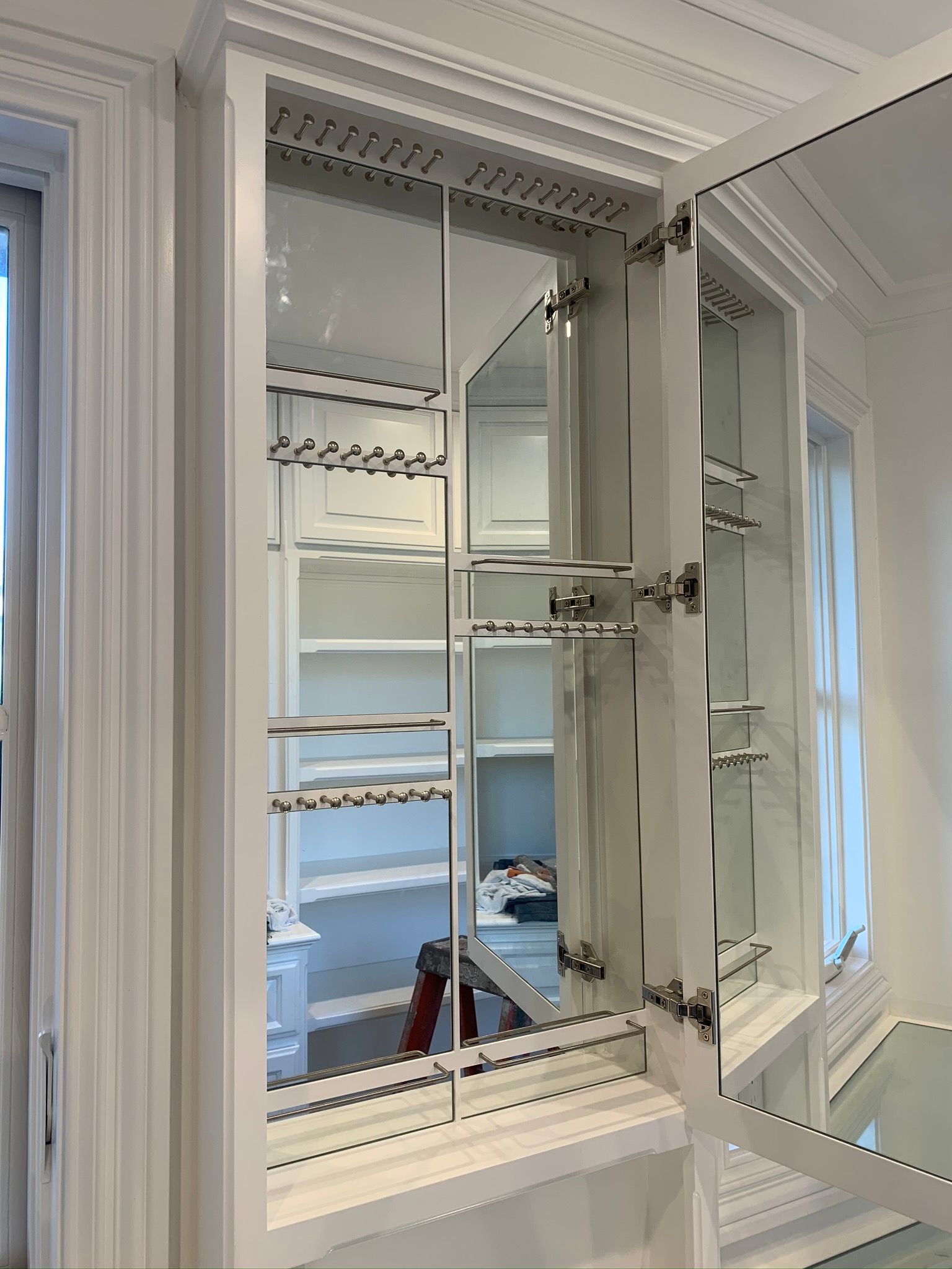 Built-in white cabinet with mirrored doors and shelving. One door is open.