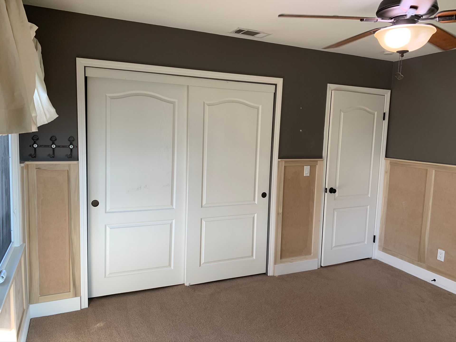 Bedroom with white doors, brown carpet, and a dark gray wall.