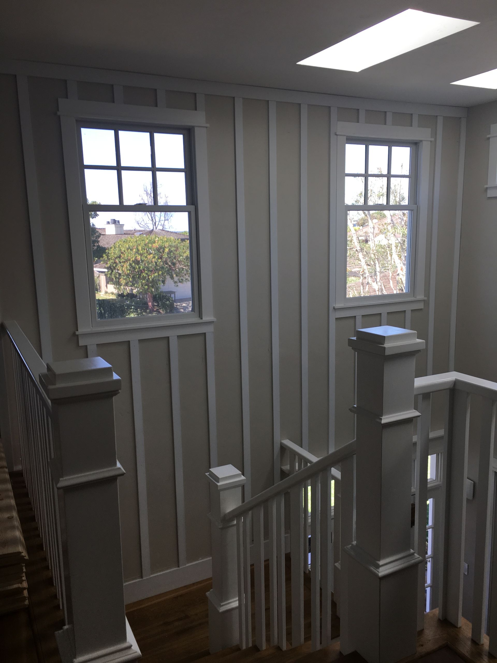 Interior staircase with two windows and vertical wall paneling.