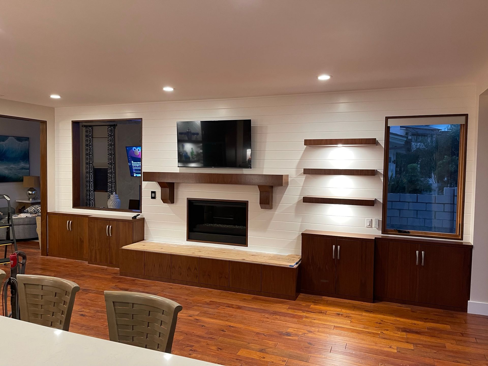 A built-in entertainment center with a fireplace, TV, shelves, and cabinets in a living room.