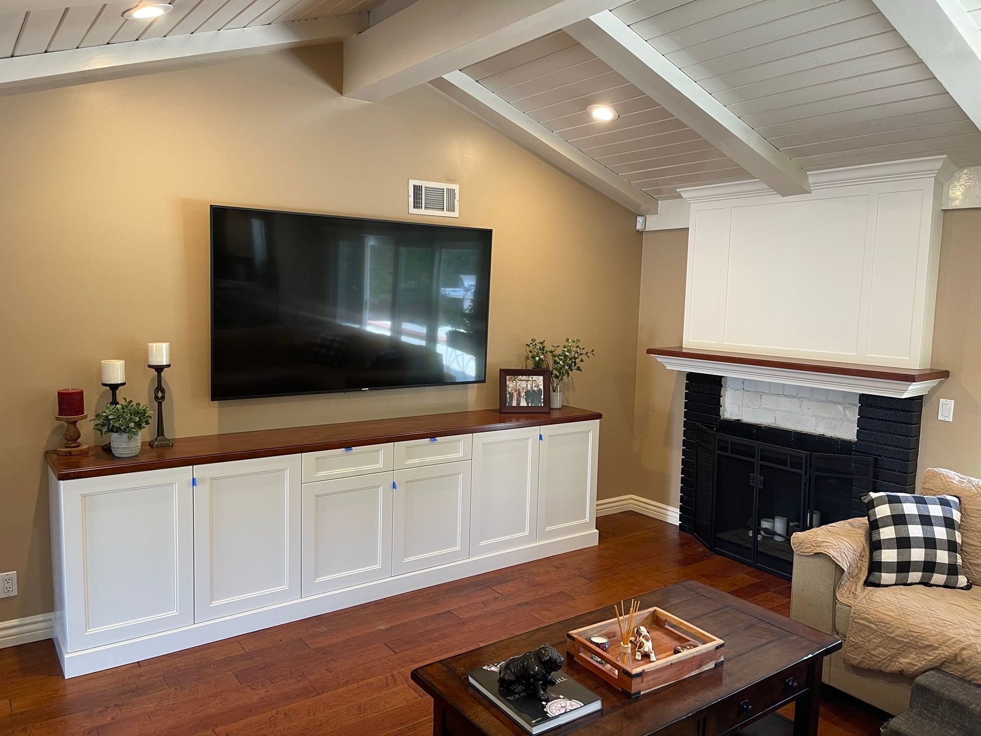 Living room with vaulted ceiling, TV above a cabinet, fireplace, and coffee table.