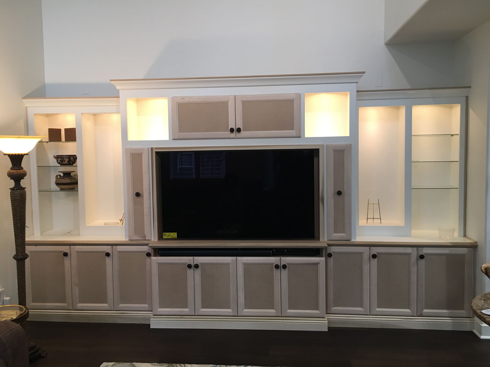 Built-in entertainment center with TV, cabinetry, and shelving in a living room.