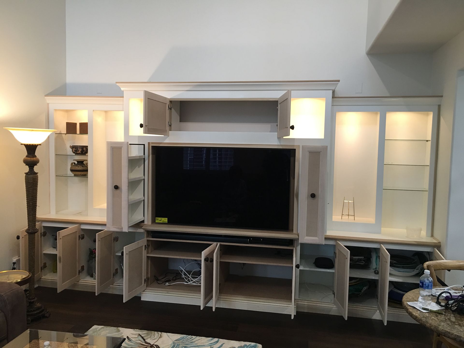 Cream-colored built-in entertainment center with open cabinets and TV, set against a white wall.