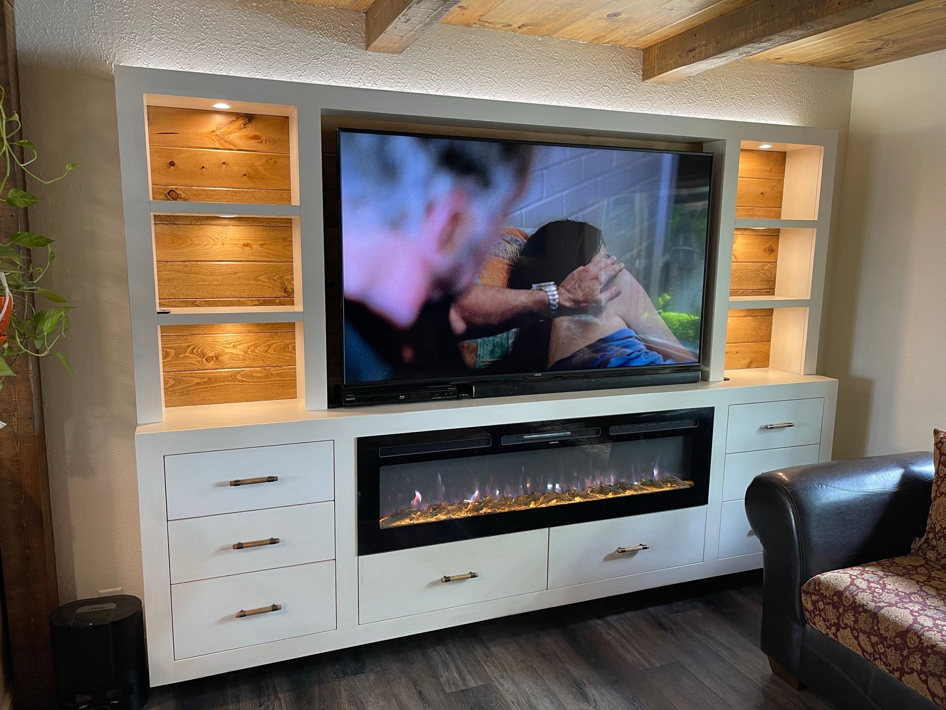 White media center with a TV, electric fireplace, shelving, and drawers.