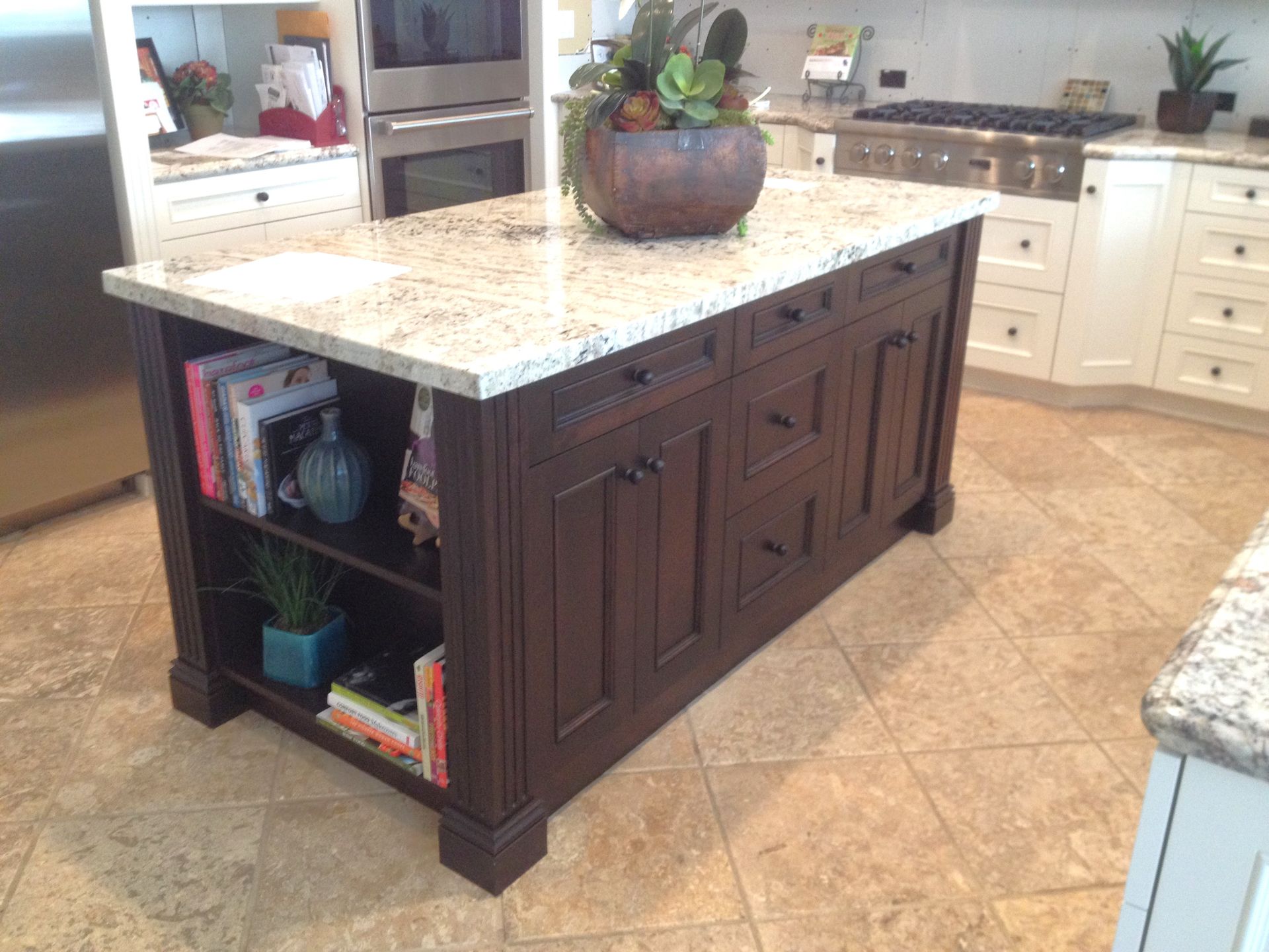 Kitchen island with dark wood cabinets, granite countertop, and decorative items.