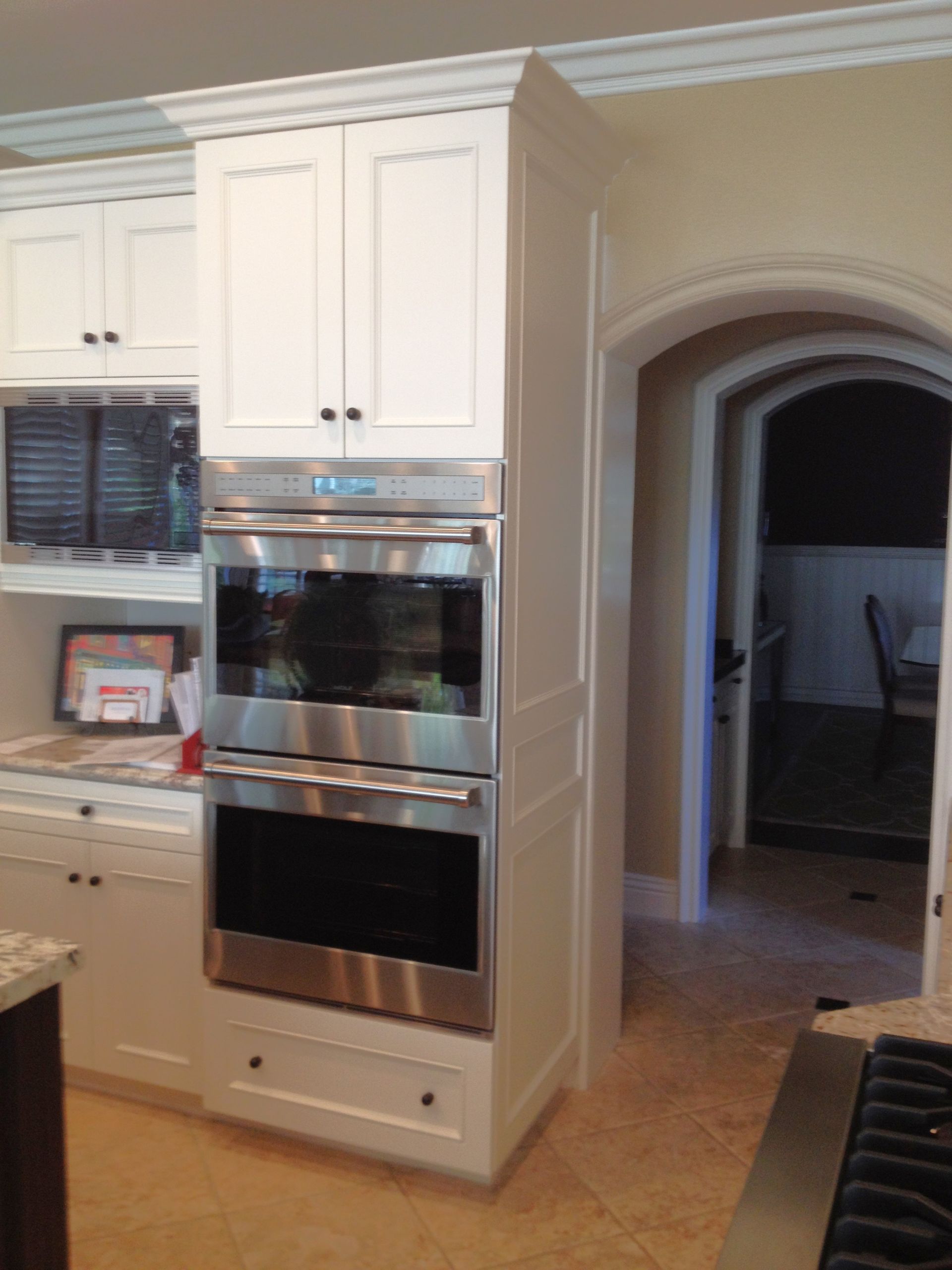 White kitchen cabinets with built-in stainless steel double oven.