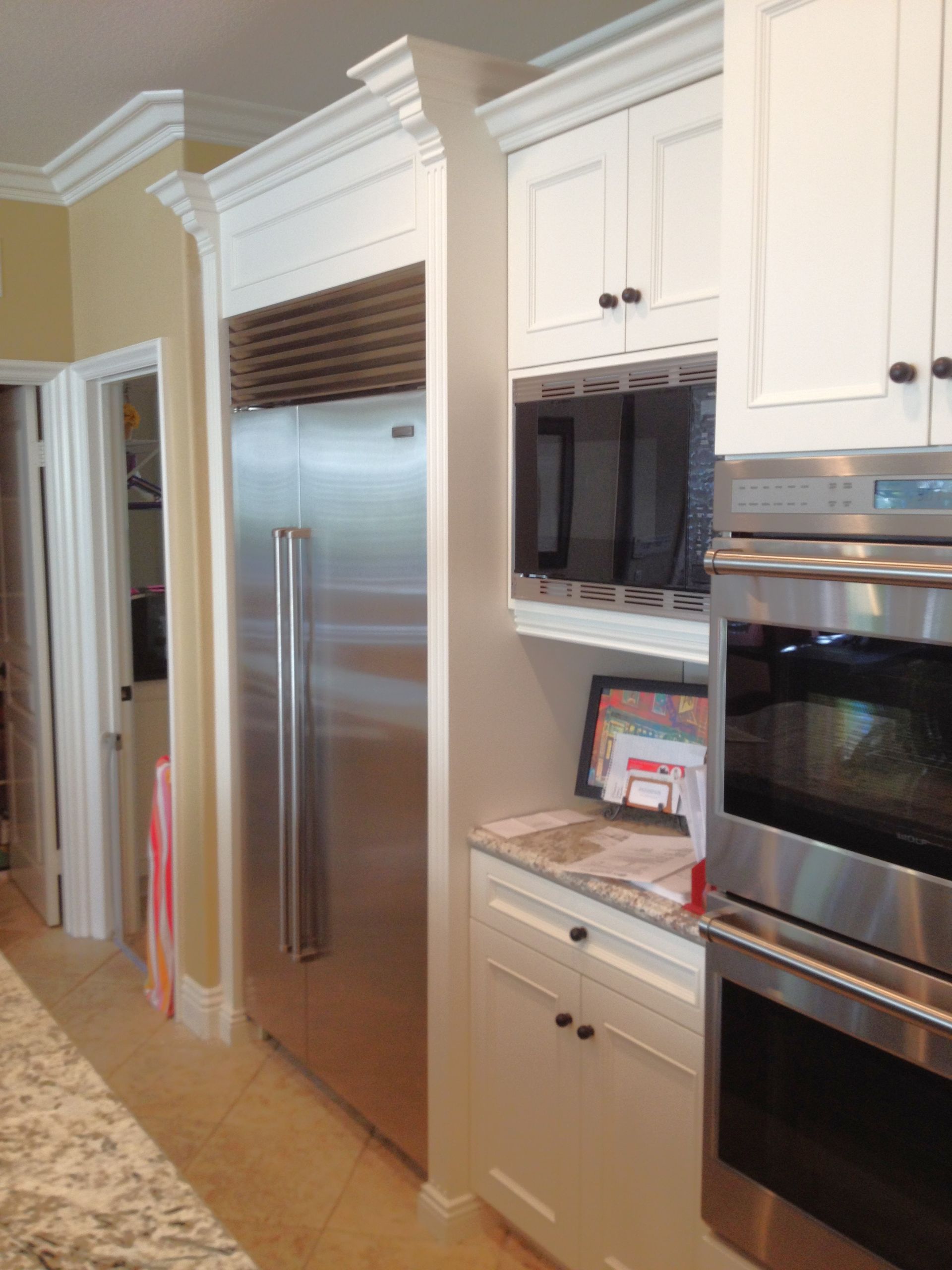 Kitchen with white cabinets, stainless steel refrigerator and oven.
